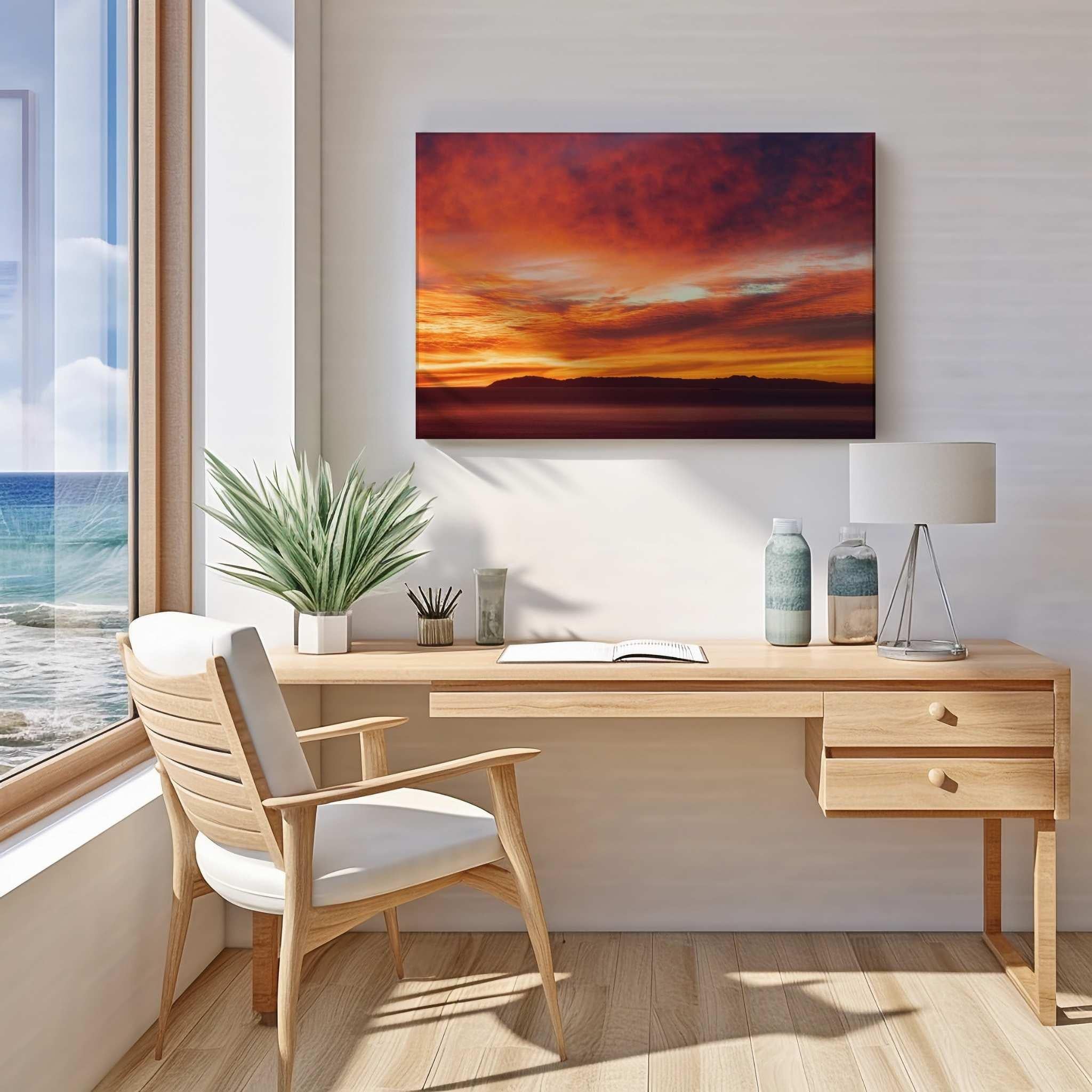 Modern home office featuring a gallery-wrapped canvas of a dramatic California sunset with vibrant red, orange, and gold skies above the Pacific Ocean. Artwork by Abigail Diane Photography.