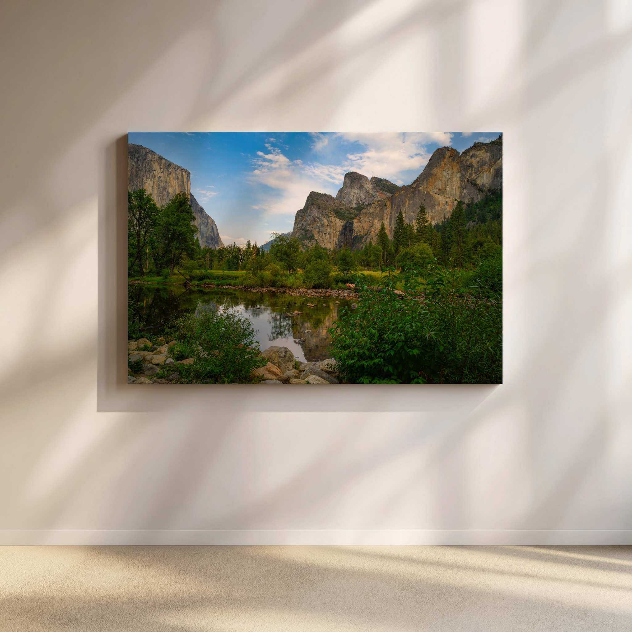 Large gallery-wrapped canvas of A Majestic Day in Yosemite Valley displayed in a bright modern organic living room with soft natural light, showcasing Yosemite National Park's iconic granite cliffs, tranquil river reflections, and lush green meadows in California. Artwork by Abigail Diane Photography.