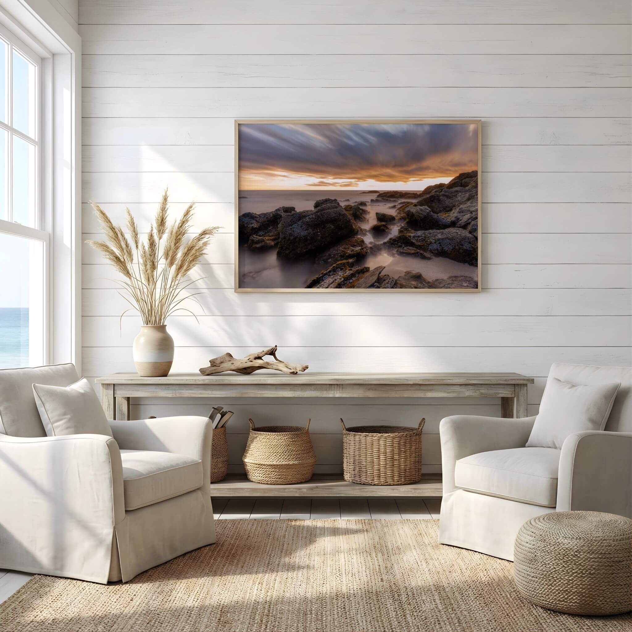 Laguna Beach coastal landscape print displayed above a coastal console table, showcasing rugged shoreline rocks, flowing ocean water, and dramatic sunset skies.