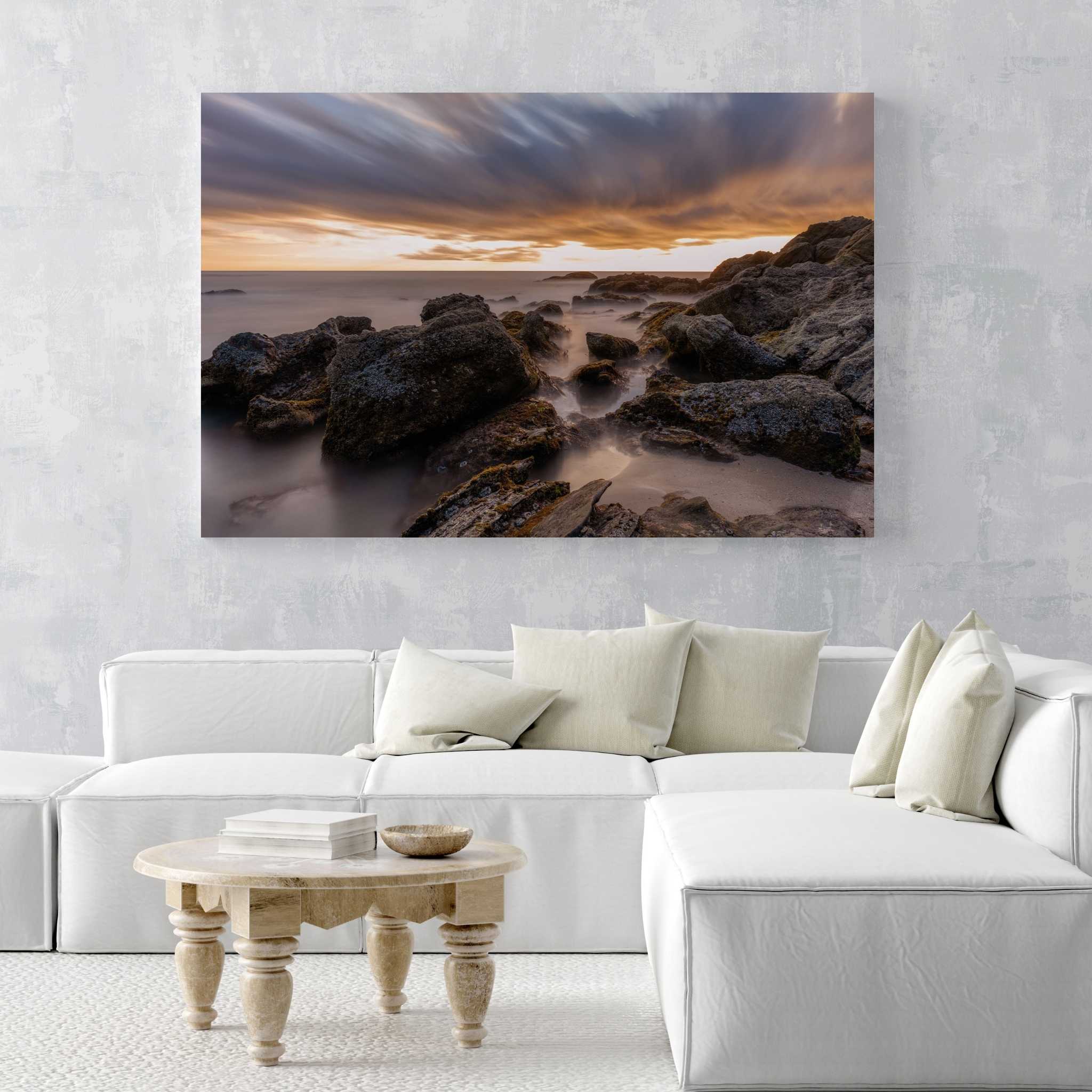After the Storm HD metal print by Abigail Diane Photography displayed above a white sectional sofa in a modern coastal living room, showcasing dramatic sunset skies and rugged shoreline at Laguna Beach, California.