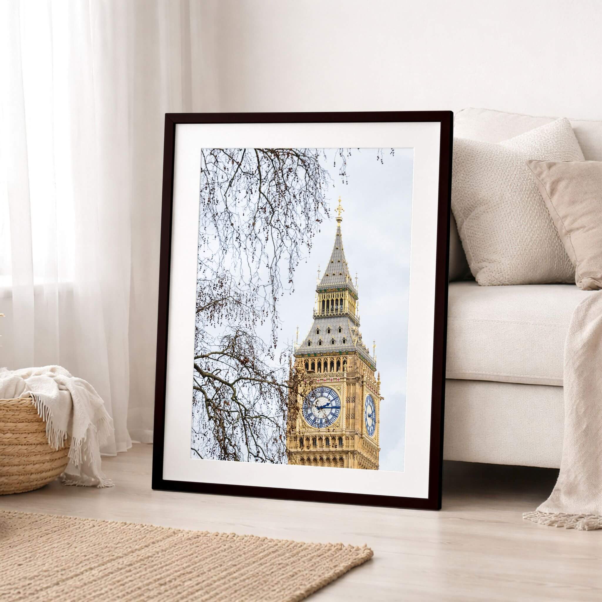 Framed fine art print of Big Ben leaning against a wall beside a sofa, highlighting London's iconic landmark in a warm, modern home setting.