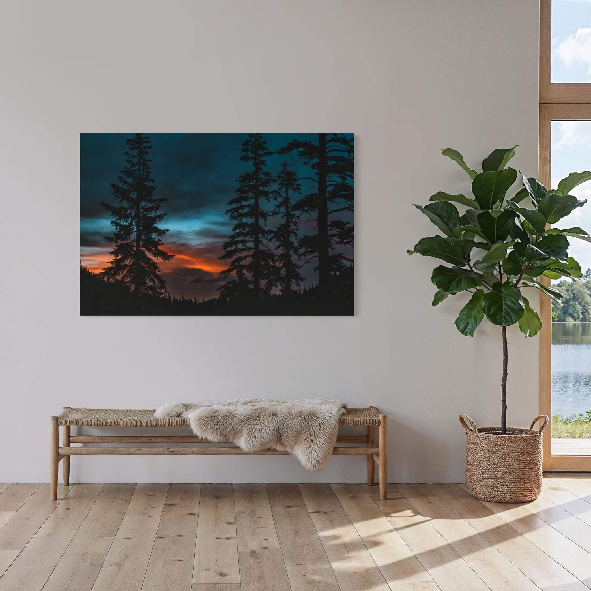 Blue Hour Among the Pines forest sunset wall art displayed above a wooden bench in a minimalist entryway with a large indoor fiddle-leaf fig.
