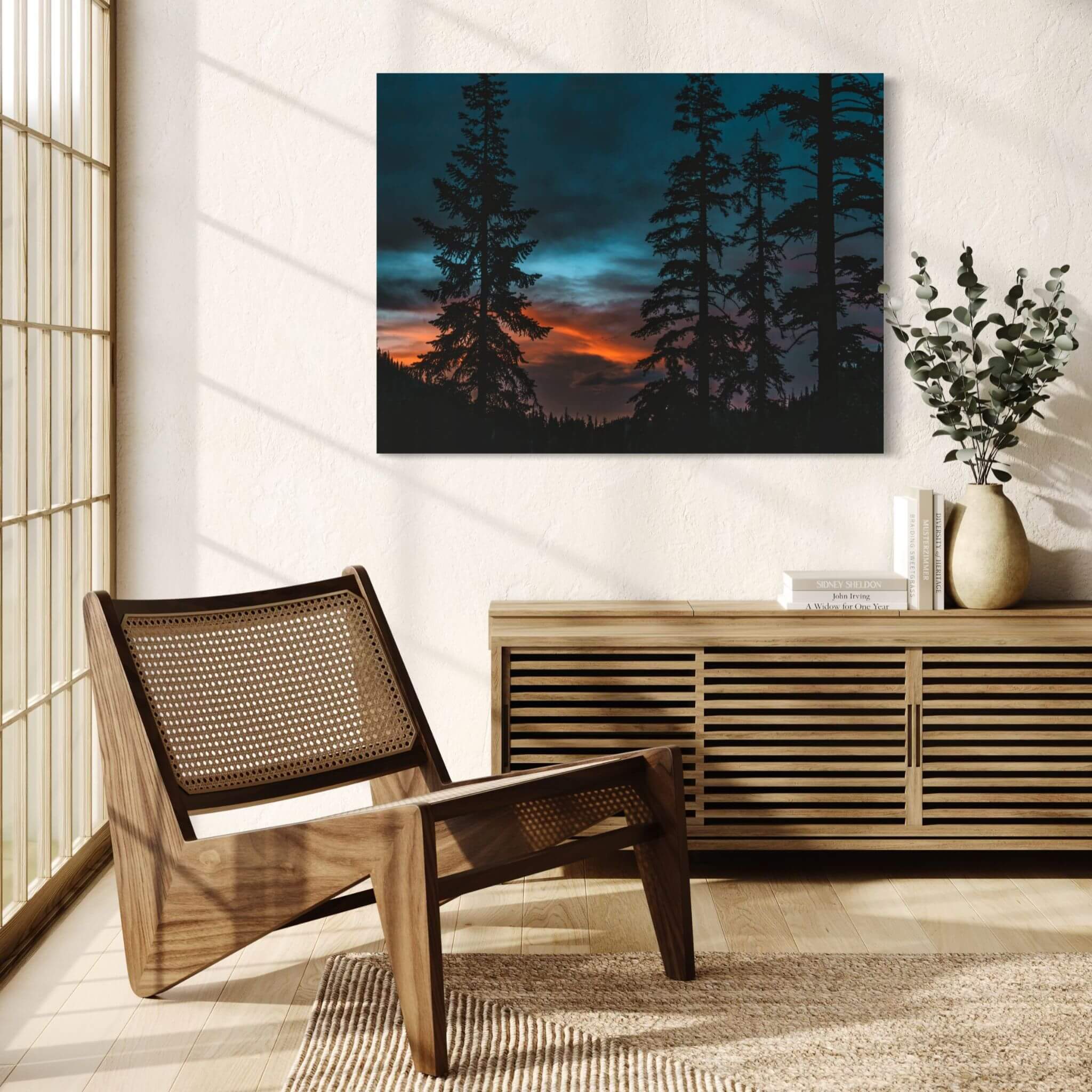 Blue Hour Among the Pines woodland sunset wall art displayed above a natural wood sideboard in a bright reading room with warm morning light.