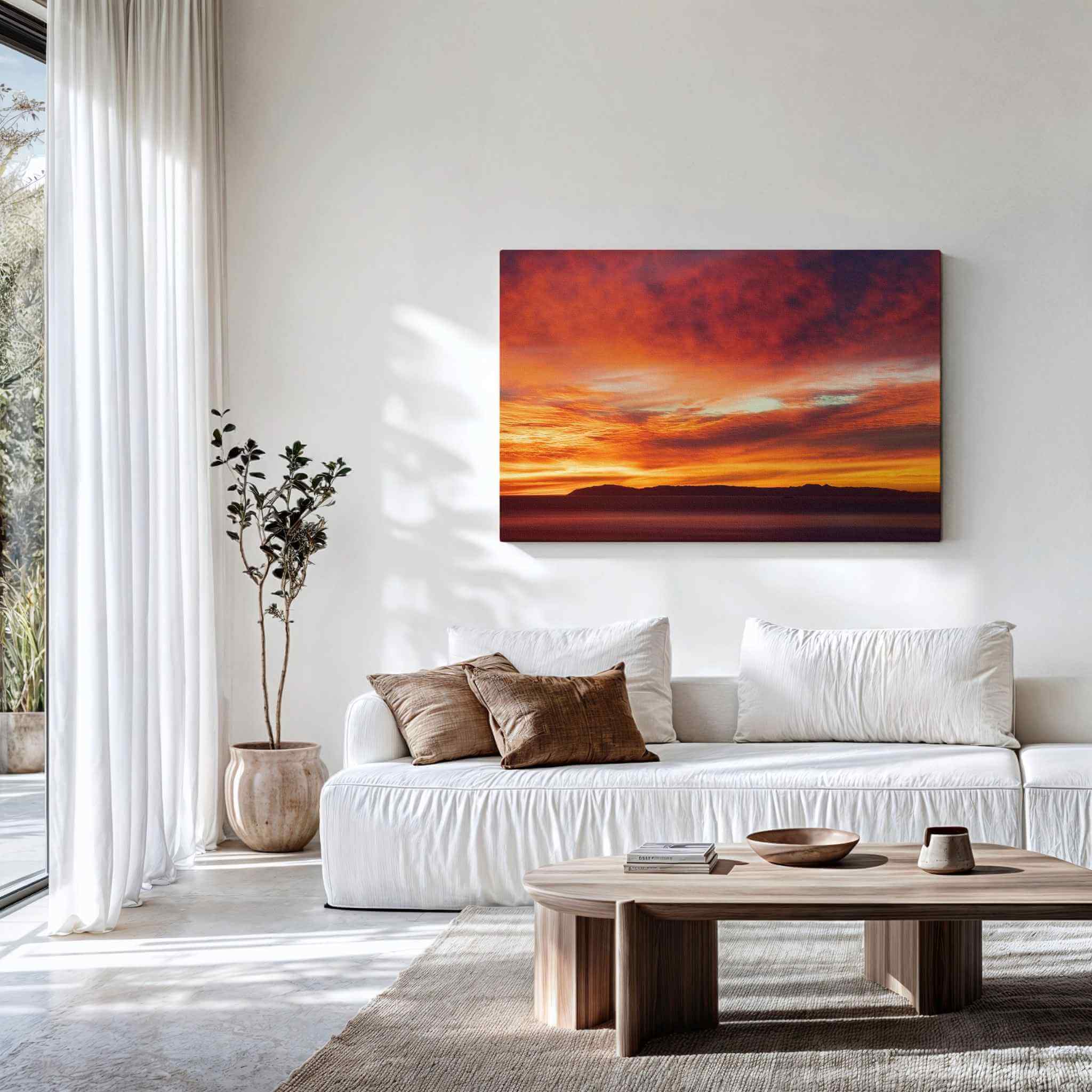 Gallery wrapped canvas of Catalina Beneath Crimson Skies displayed above a contemporary white sofa, showcasing a dramatic crimson sunset over Catalina Island viewed from Laguna Beach, California. Fine art wall decor by Abigail Diane Photography.