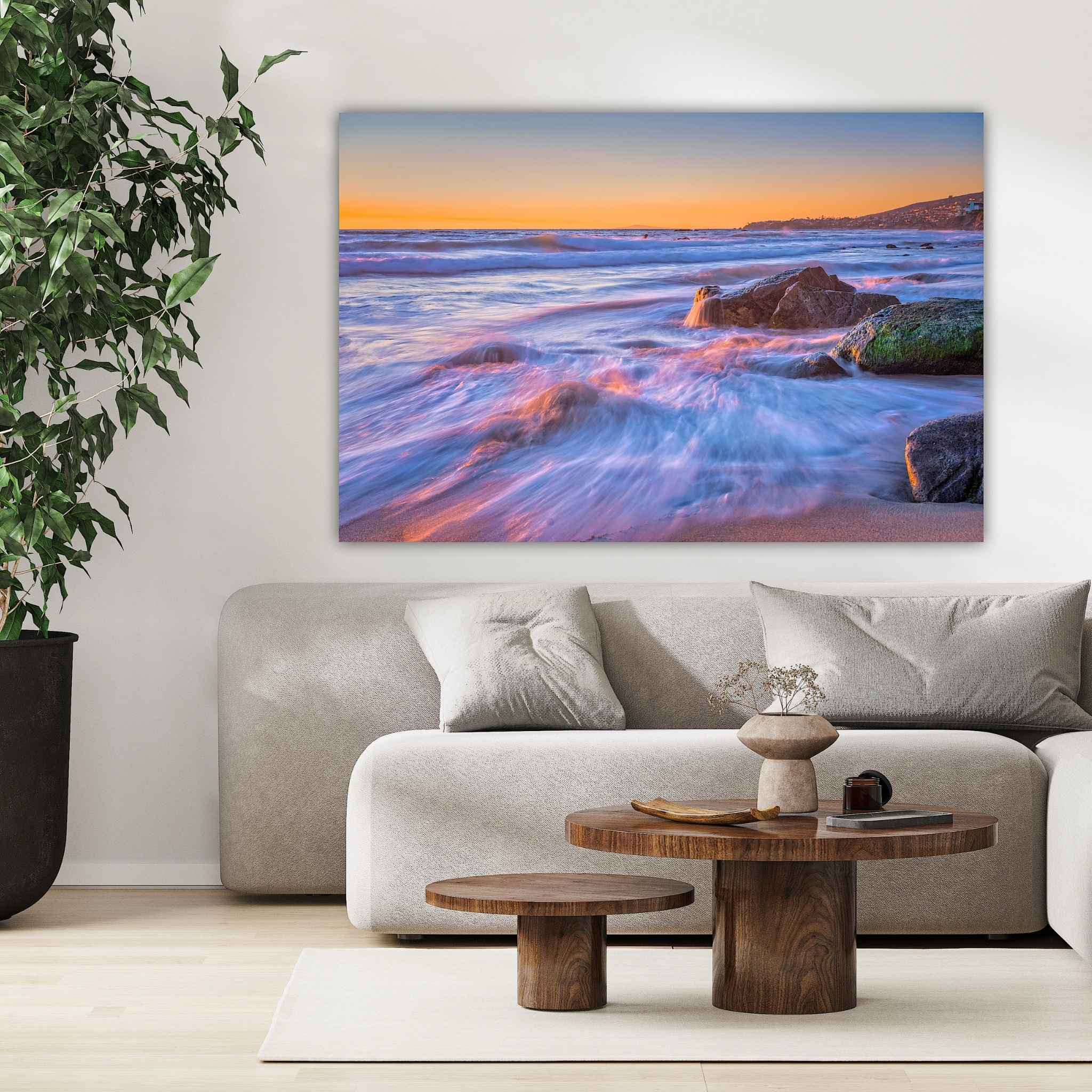 Cotton Candy Waves dye-sublimation metal print by Abigail Diane Photography displayed above a contemporary cream sofa, featuring pastel blue and pink ocean waves flowing across the shoreline at sunset in Laguna Beach, California.