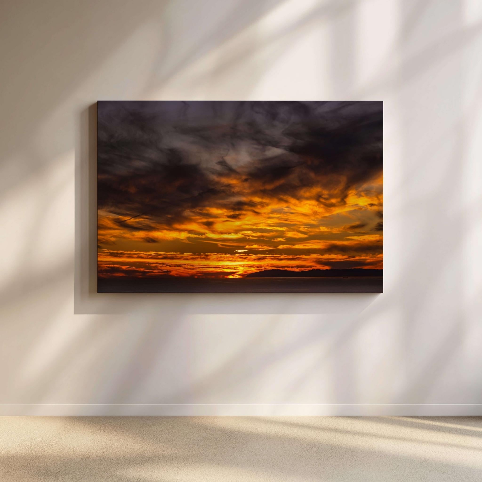 Gleaming Golden Sunset gallery-wrapped canvas by Abigail Diane Photography displayed in a contemporary minimalist living room. A majestic golden sunset over Catalina Island in the Pacific Ocean fills the sky with glowing amber, gold, and deep charcoal clouds, creating a dramatic coastal focal point and a warm, inviting atmosphere.