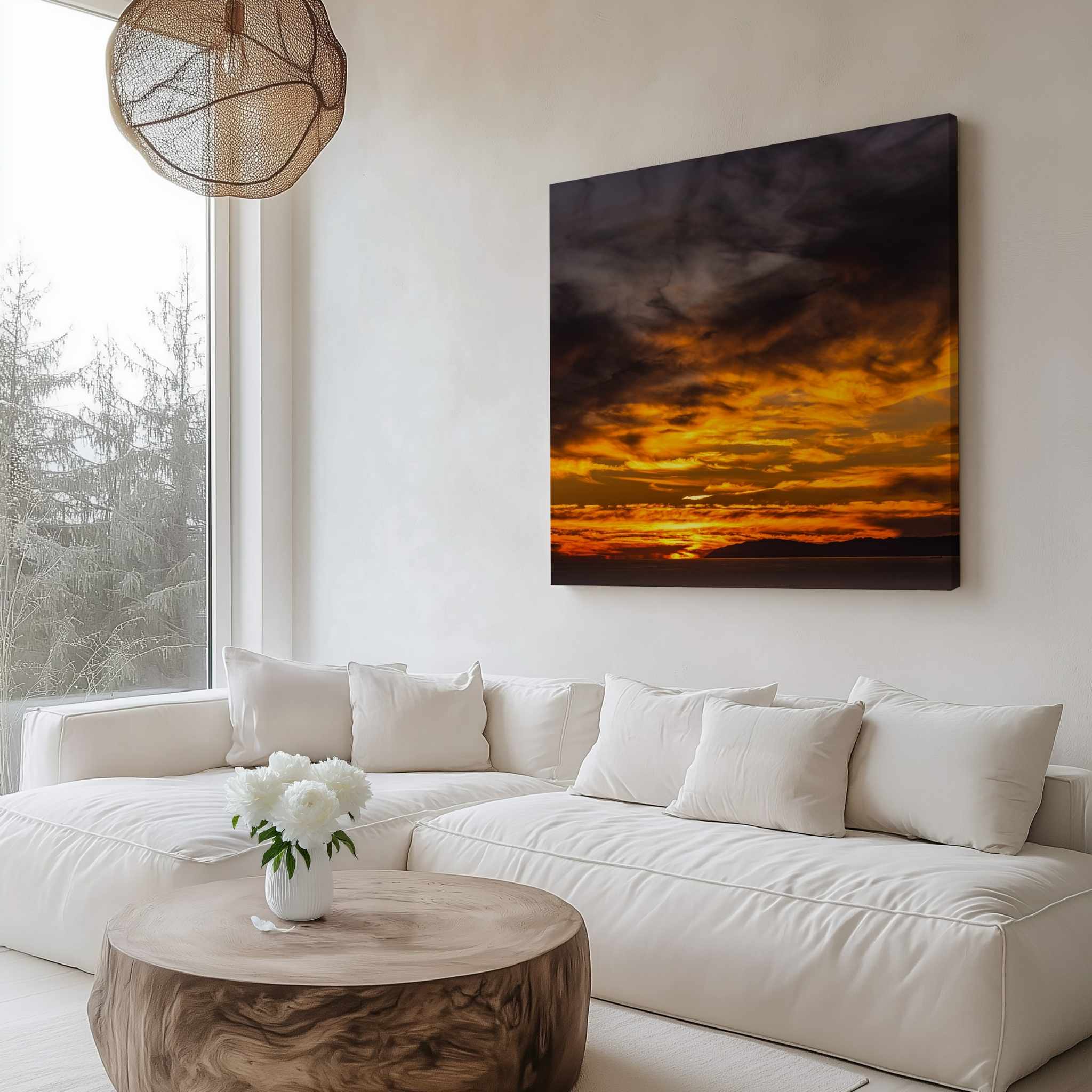 Gallery wrapped canvas featuring a dramatic golden sunset displayed above a curved white sofa in a bright modern living room with a wooden coffee table.