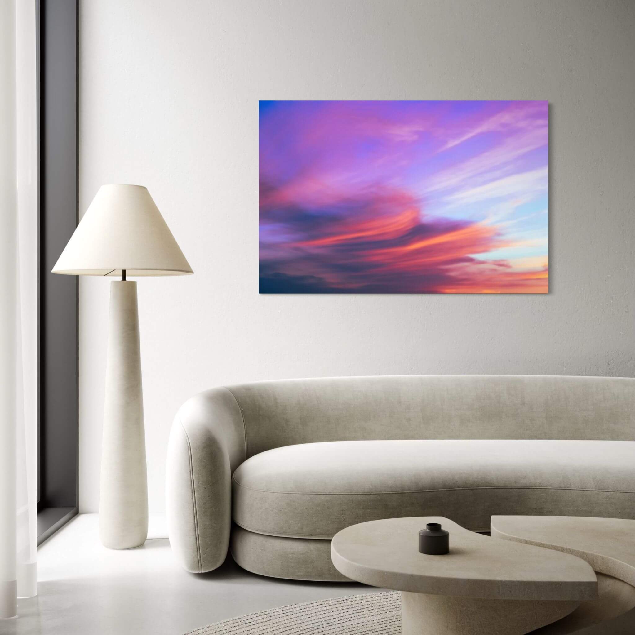 Lavender Dreams HD metal wall art displayed above a curved sofa in a modern lounge, showcasing vibrant lavender, pink, coral, and blue sunset clouds by Abigail Diane Photography.