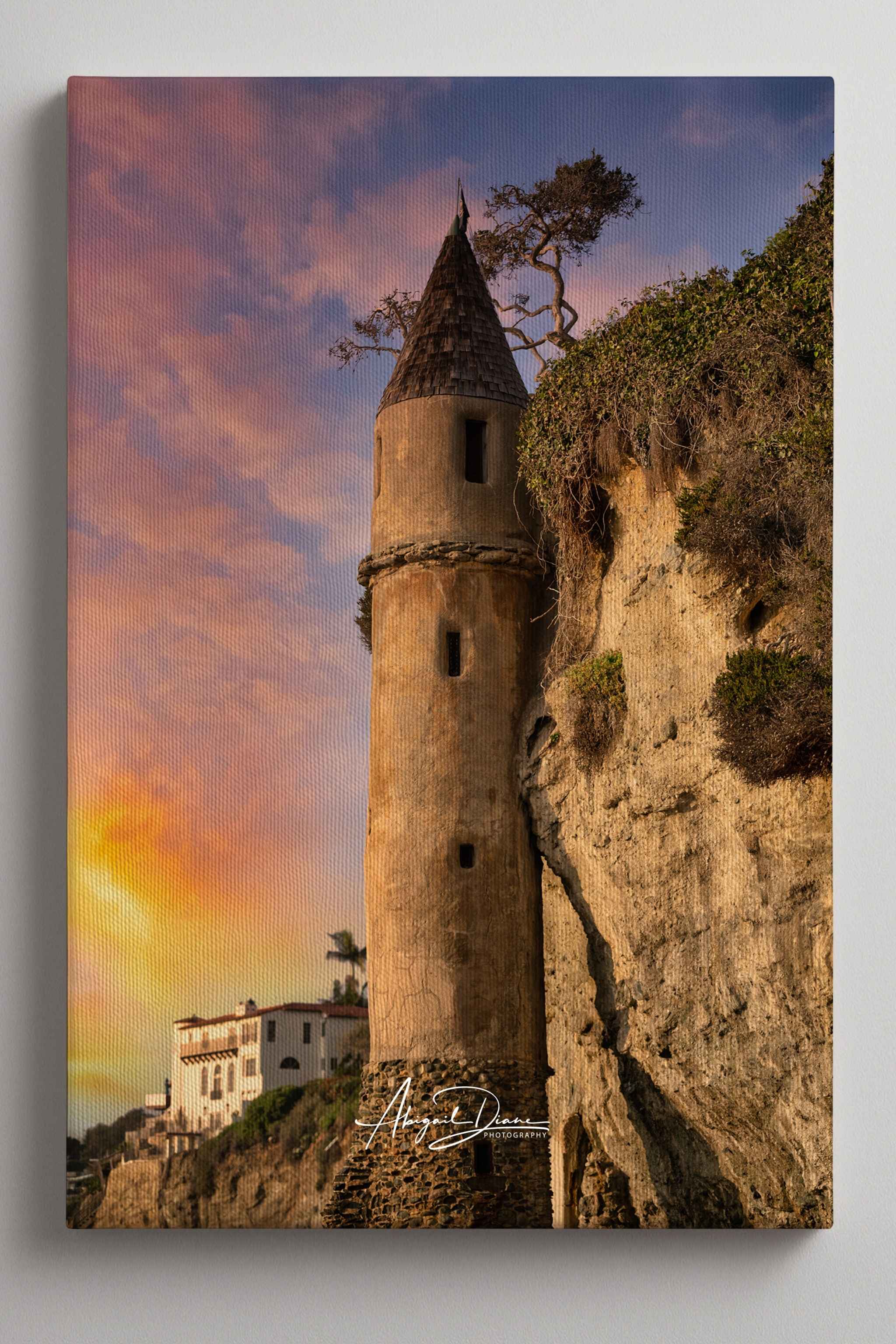 Let Your Hair Down canvas print featuring the iconic Pirate Tower at Victoria Beach in Laguna Beach, California, illuminated by warm golden light beneath soft pink and lavender sunset clouds, with Abigail Diane Photography branding.