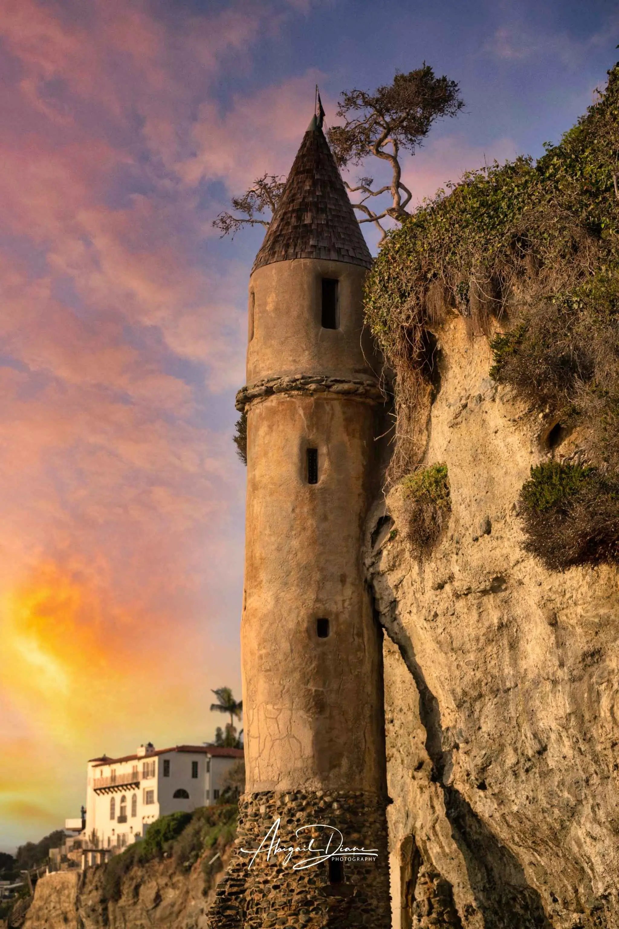 Sunset photograph of the historic Pirate Tower at Victoria Beach in Laguna Beach California featuring glowing pastel skies, rugged coastal cliffs, and the mysterious castle-like tower inspired by the story of Rapunzel, photographed by Abigail Diane Photography.