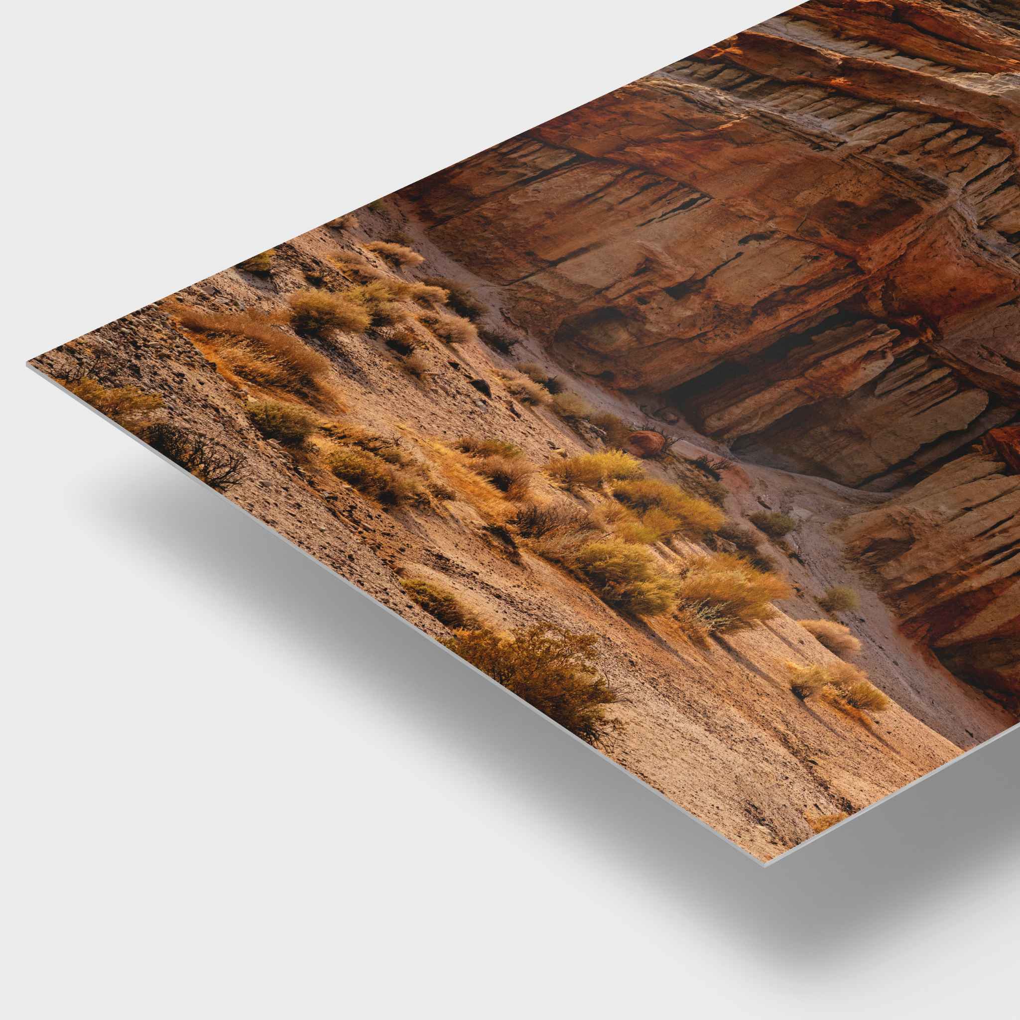 A corner piece of sculpted by time wall art HD metal print showing a desert canyon landscape, photographed at an angle on a light gray background with a soft drop shadow.