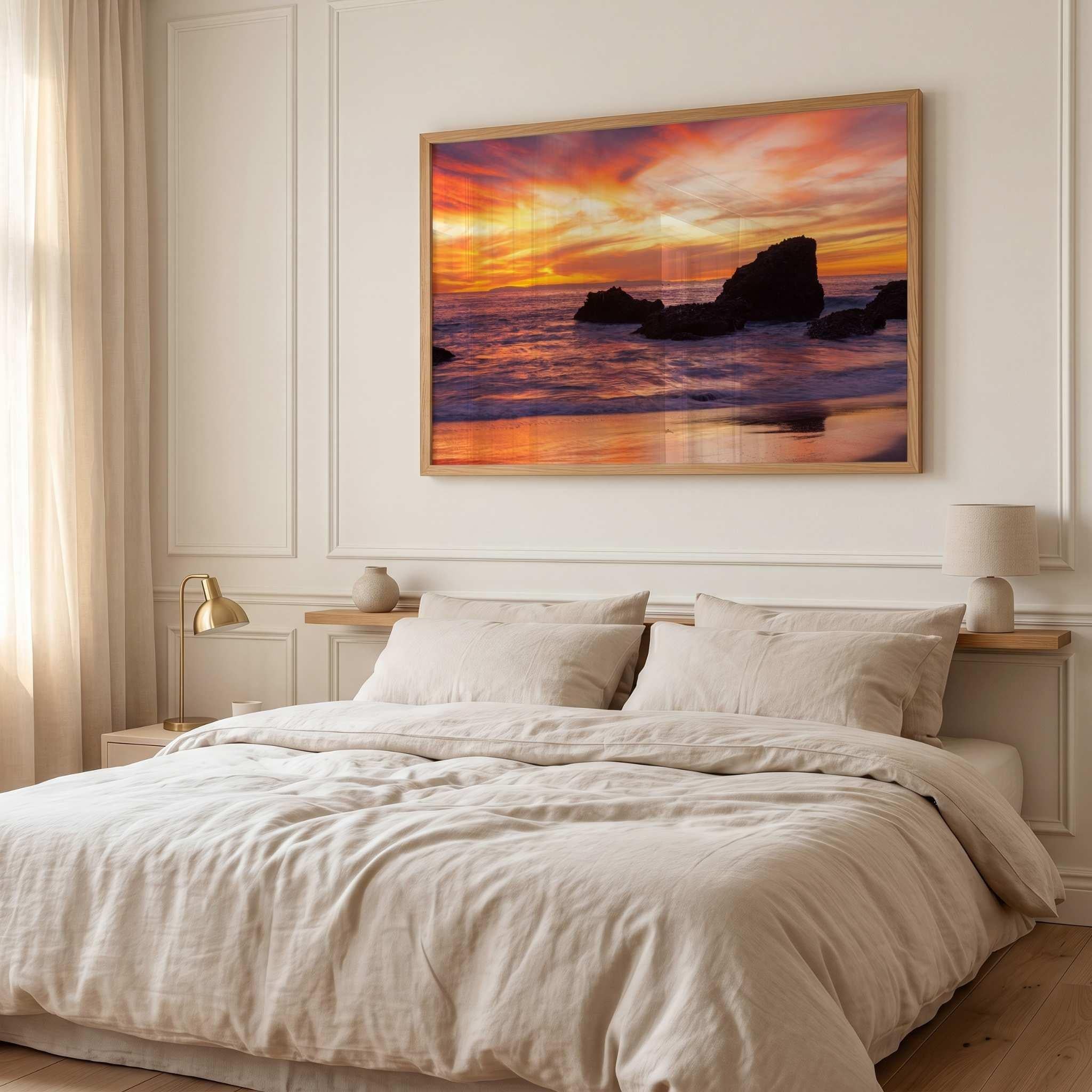 Sherbet Sunset canvas wall art by Abigail Diane Photography displayed above a bed in a serene neutral bedroom, showcasing a colorful Laguna Beach, California sunset with warm orange, pink, and purple skies.