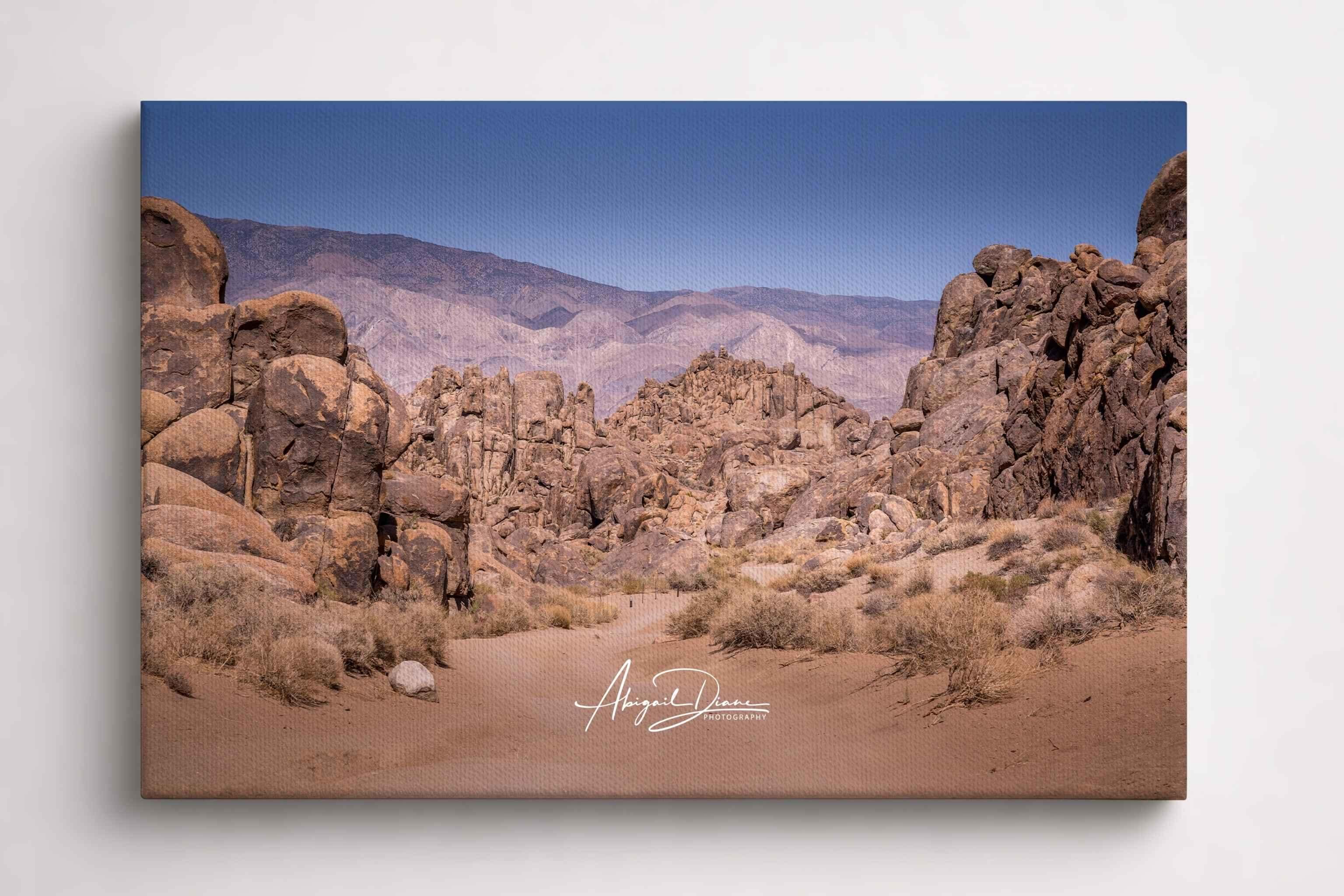 Sierra Desert Passage landscape featuring rugged rock formations and a sandy desert trail beneath a clear blue sky in the Eastern Sierra, California, displayed as a gallery-wrapped canvas print.