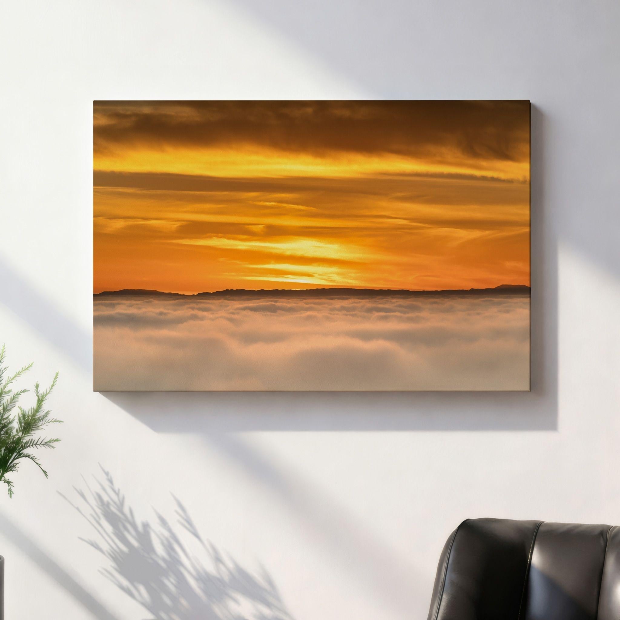 Soaring Above the Clouds gallery-wrapped canvas displayed above a contemporary sofa in a bright coastal-inspired living room, featuring a golden winter sunset above a sea of clouds. Artwork by Abigail Diane Photography.