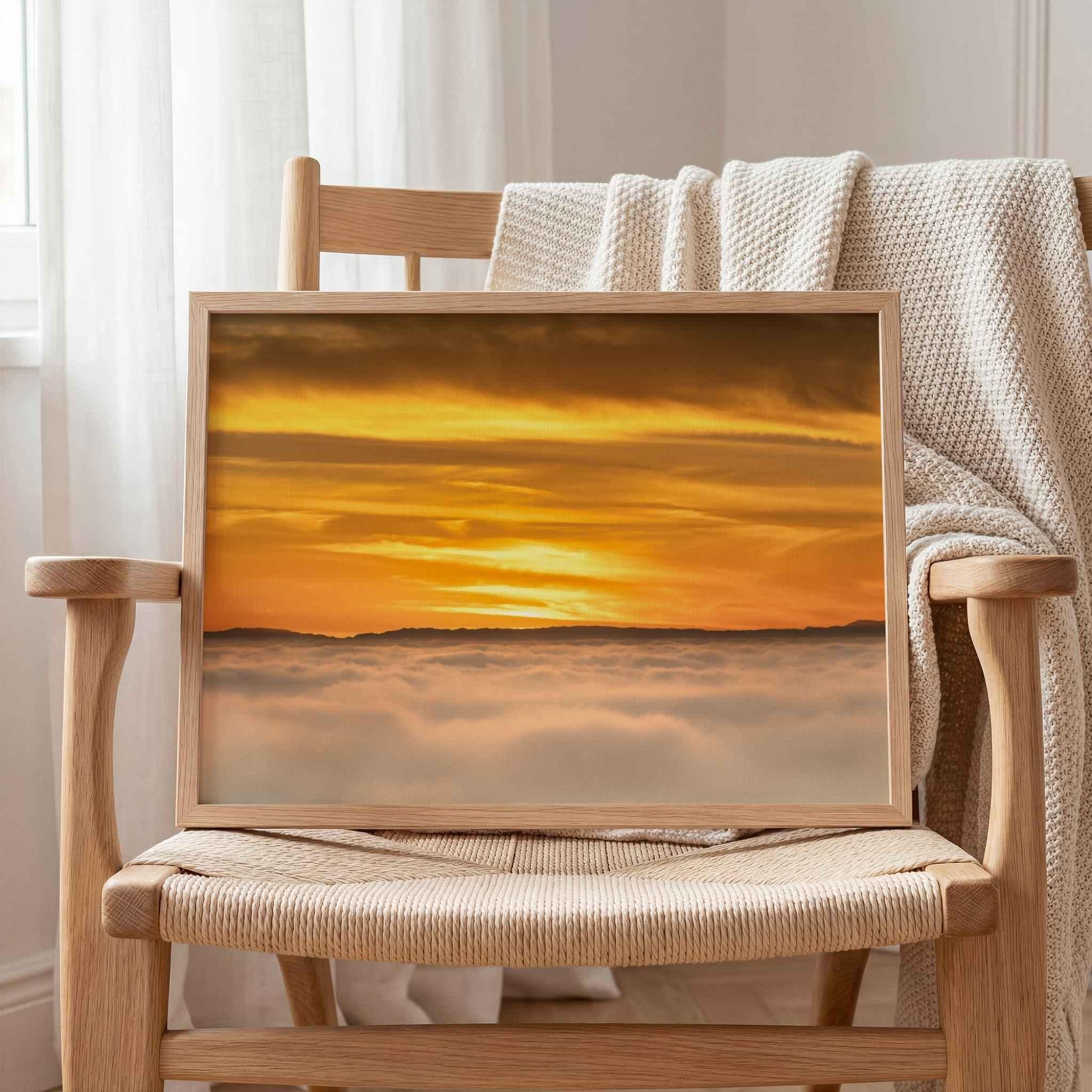 Soaring Above the Clouds framed fine art print displayed on a woven oak chair, featuring a golden winter sunset above a sea of clouds with Catalina Island on the Pacific horizon. Artwork by Abigail Diane Photography.