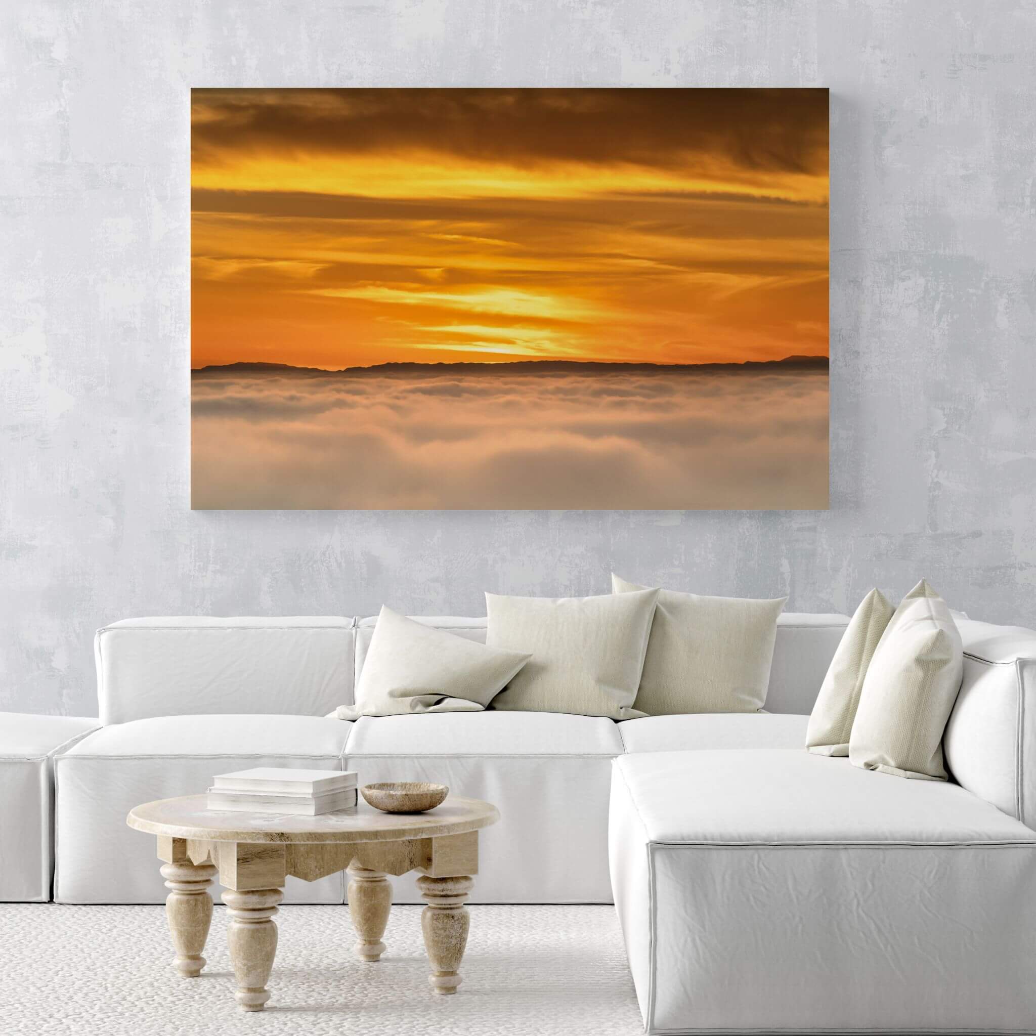 Large HD metal print of Soaring Above the Clouds by Abigail Diane Photography displayed above a modern white sofa in a minimalist living room, showcasing a golden sunset and cloudscape with brilliant clarity.