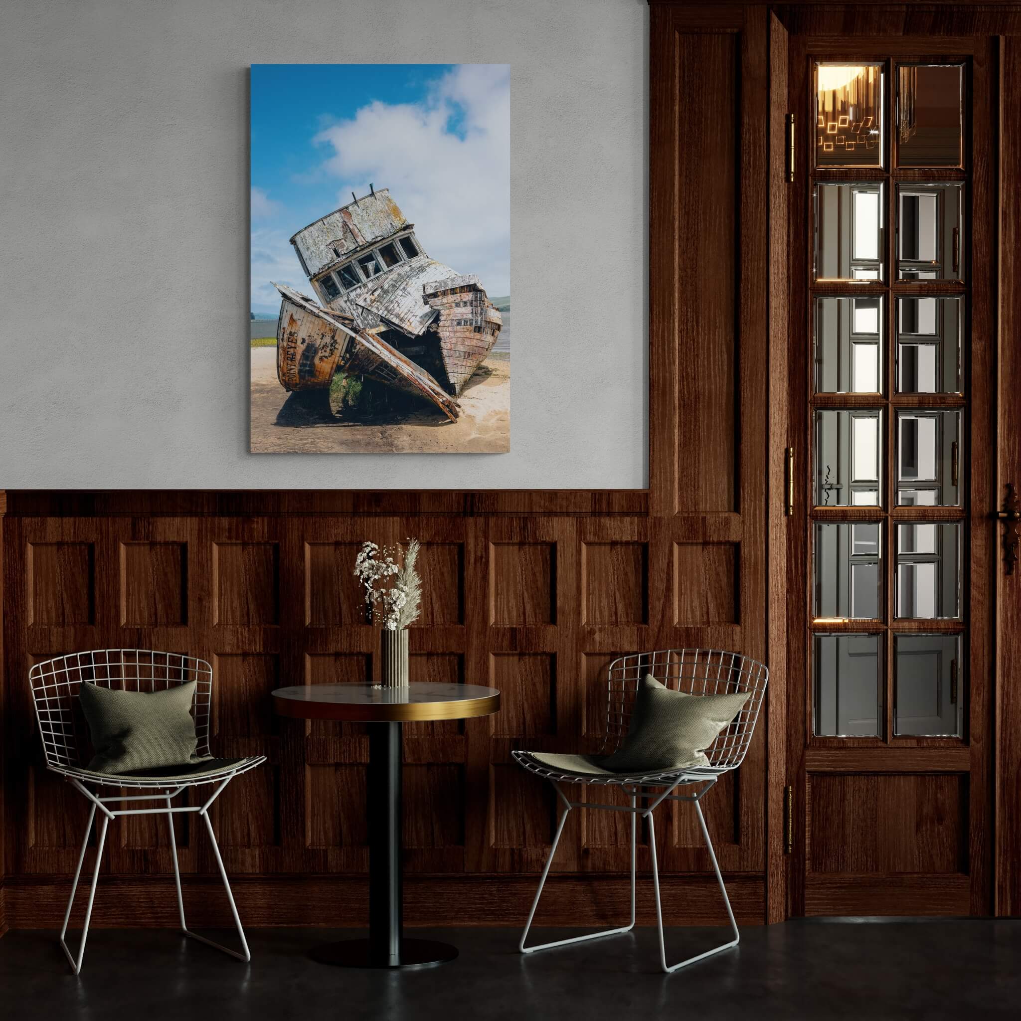S.S. Point Reyes shipwreck wall art by Abigail Diane Photography in a moody dining room with dark wood paneling, round table and modern metal chairs creating a warm atmosphere.