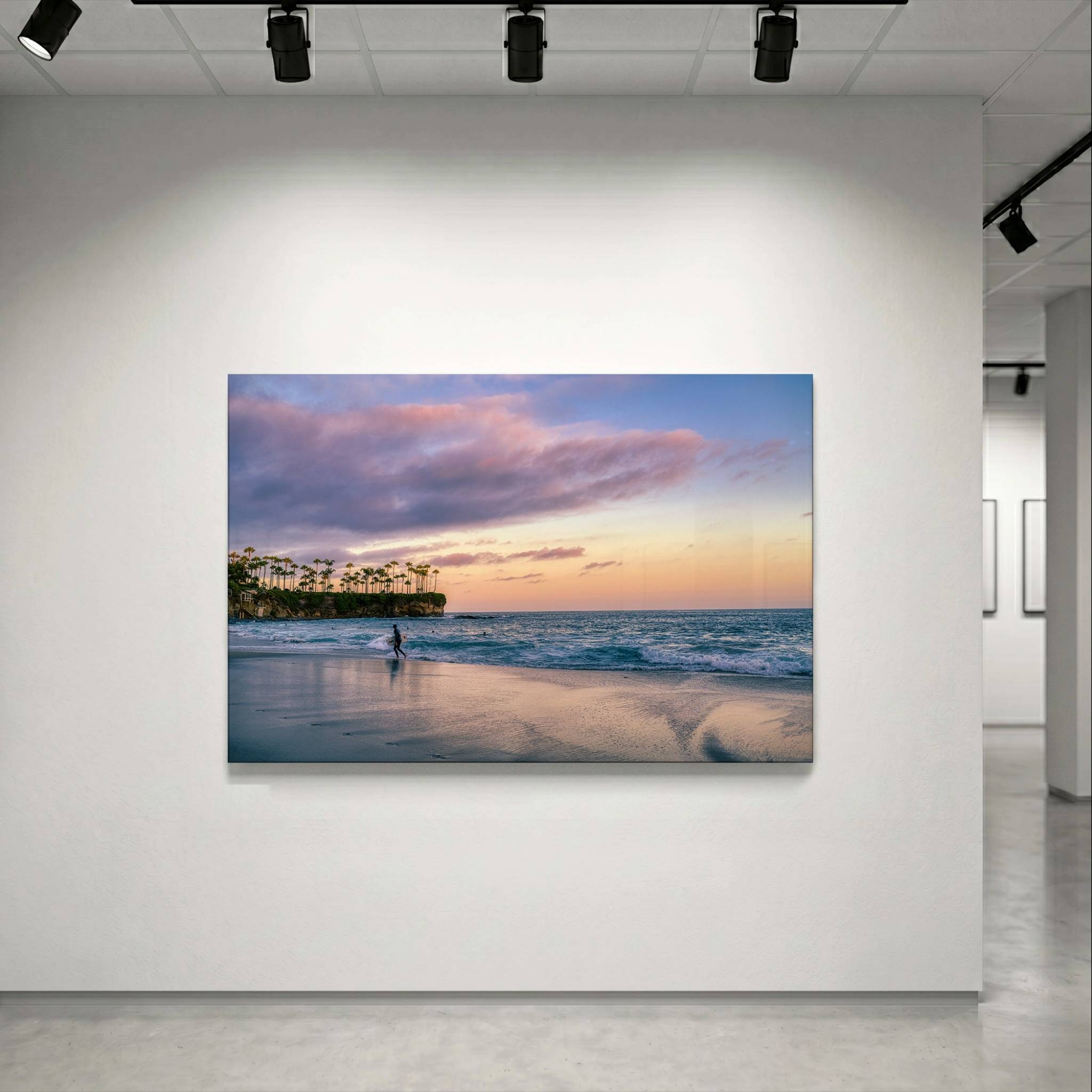 Surfing a California Sunset dye-sublimation metal print displayed in a contemporary gallery setting, featuring Crescent Beach, Laguna Beach, California. Artwork by Abigail Diane Photography.