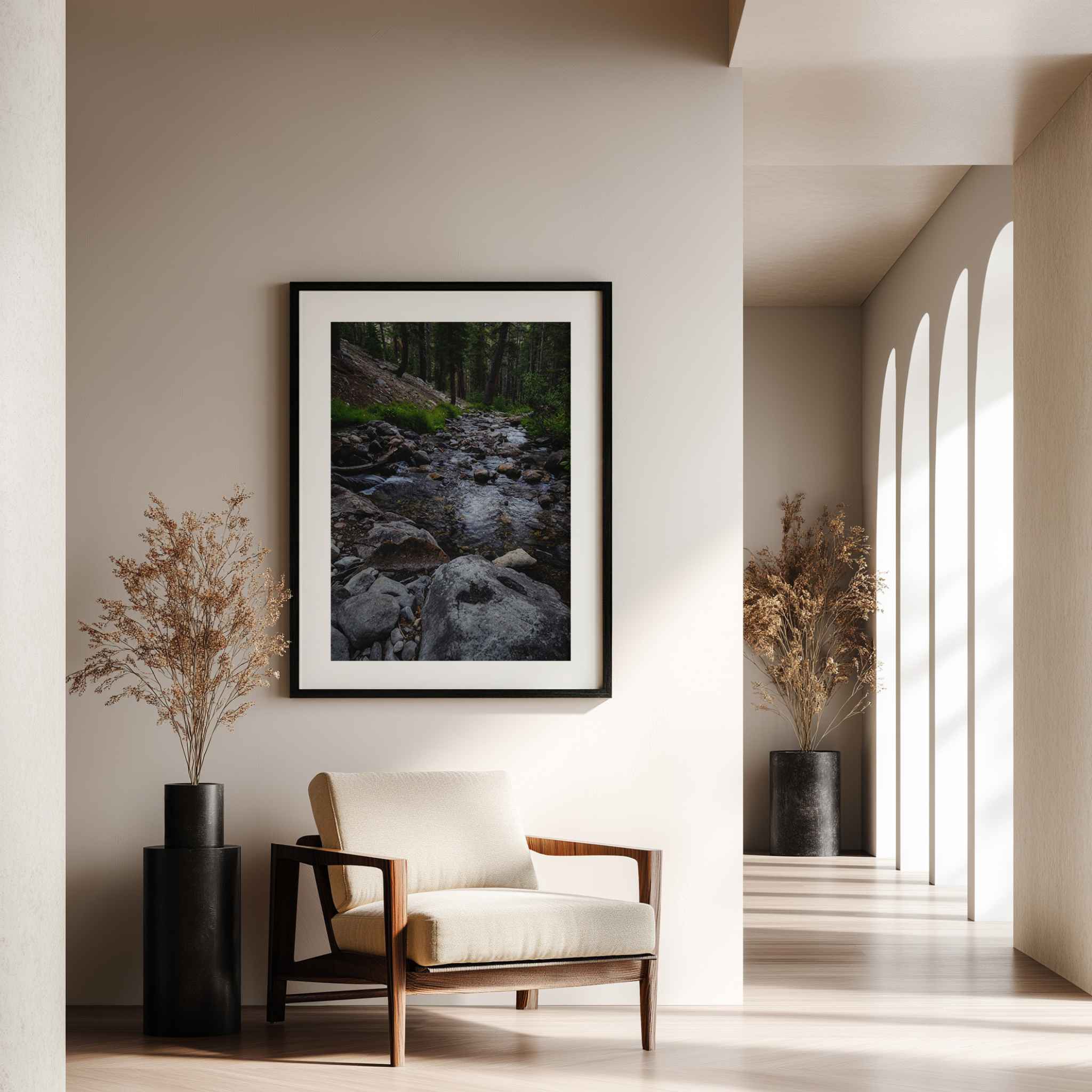 Where the Stepping Stones Lead framed fine art print featuring a peaceful rocky stream in the Eastern Sierra, California, displayed above an accent chair.