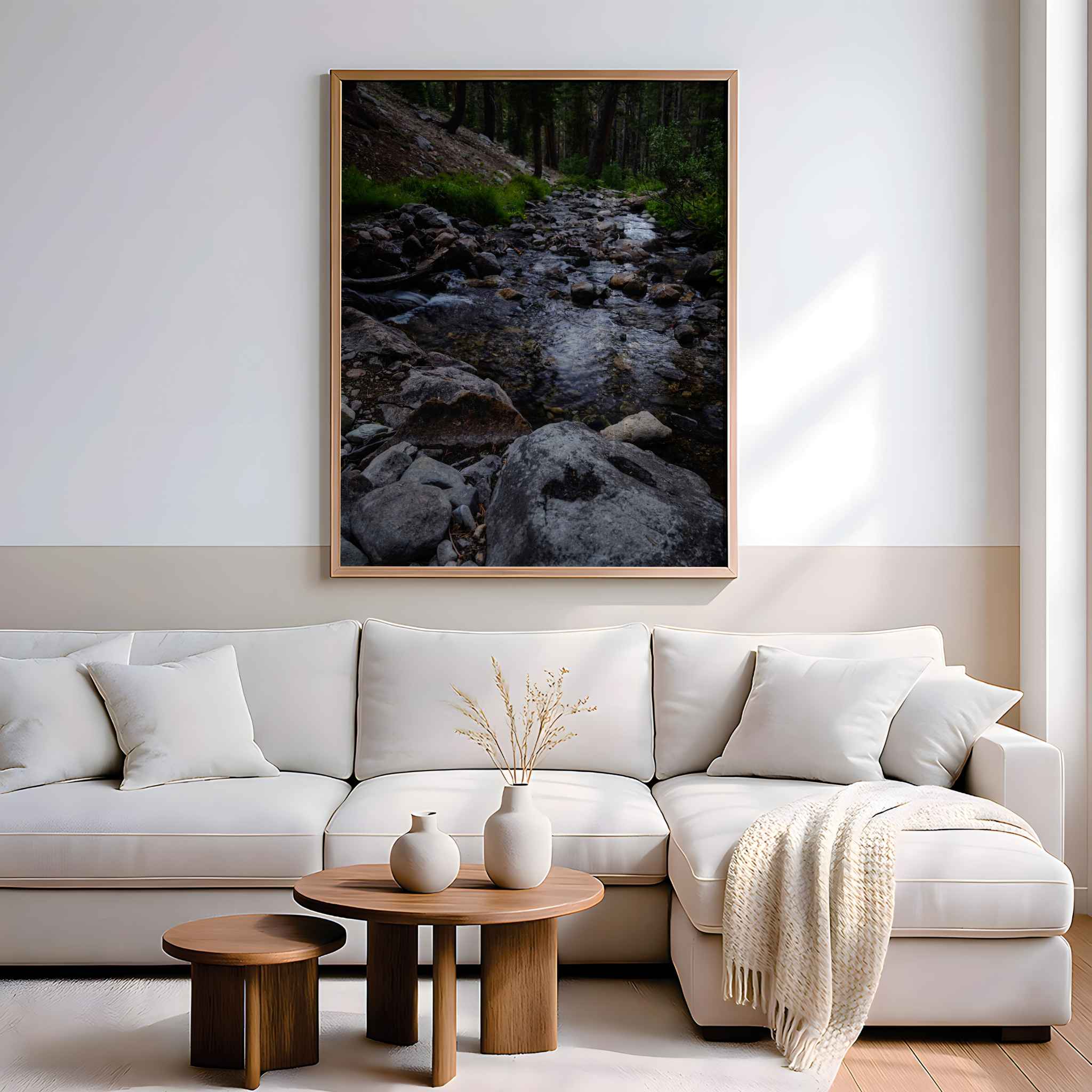 Where the Stepping Stones Lead framed wall art featuring a tranquil rocky stream in the Eastern Sierra, California, displayed above a white sectional sofa.