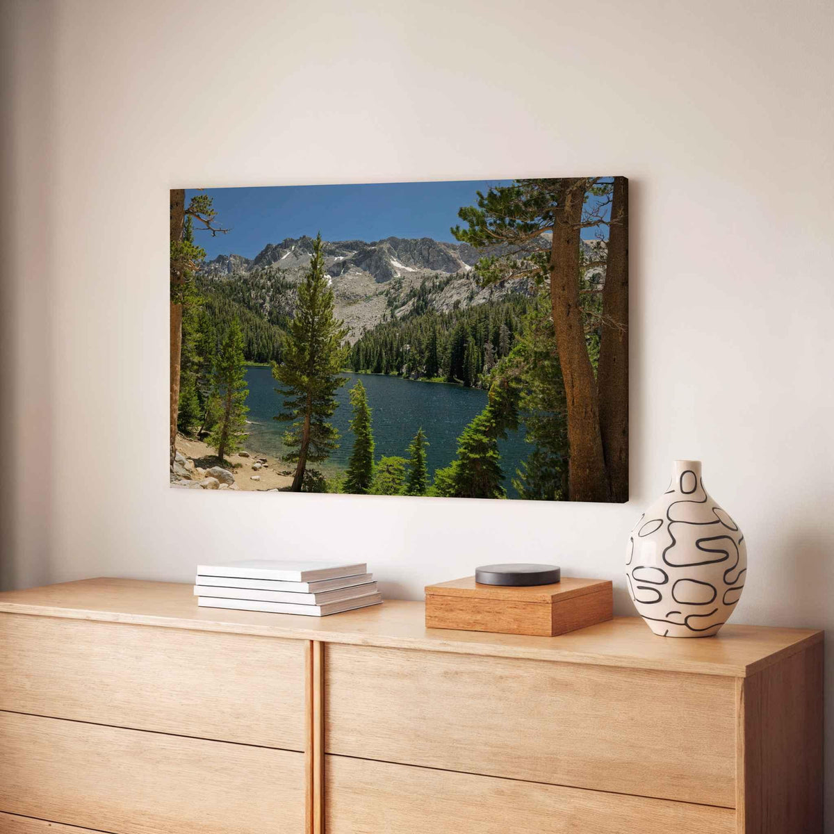 Where the Trail Gives Way to Still Waters canvas print featuring an alpine lake and mountain landscape near Mammoth Lakes in California’s Eastern Sierra, displayed above a light wood console in a warm modern interior.