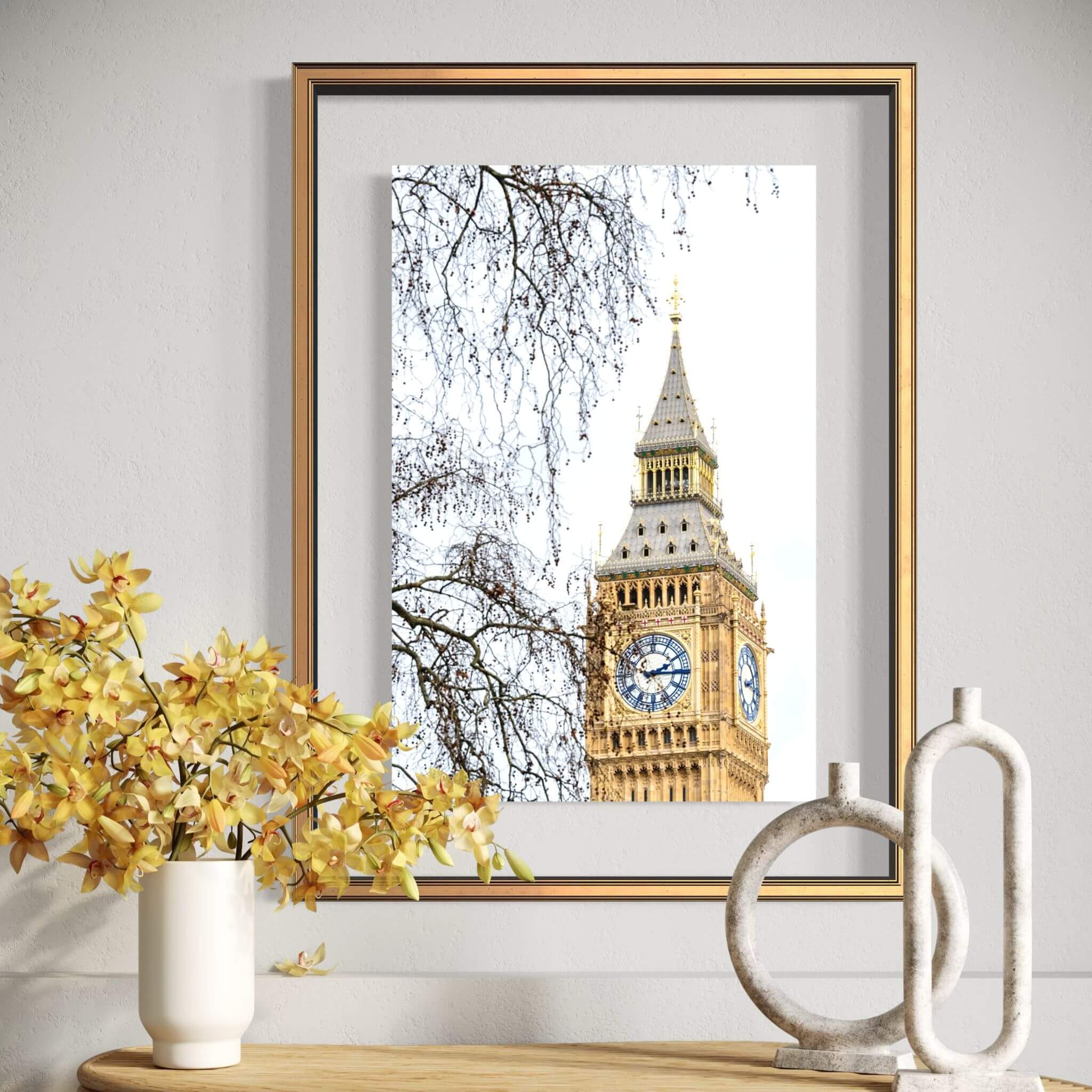 Fine art print of Big Ben in London displayed in a gold frame above a wooden console with yellow orchids, bringing timeless British architecture into a bright contemporary interior. 
