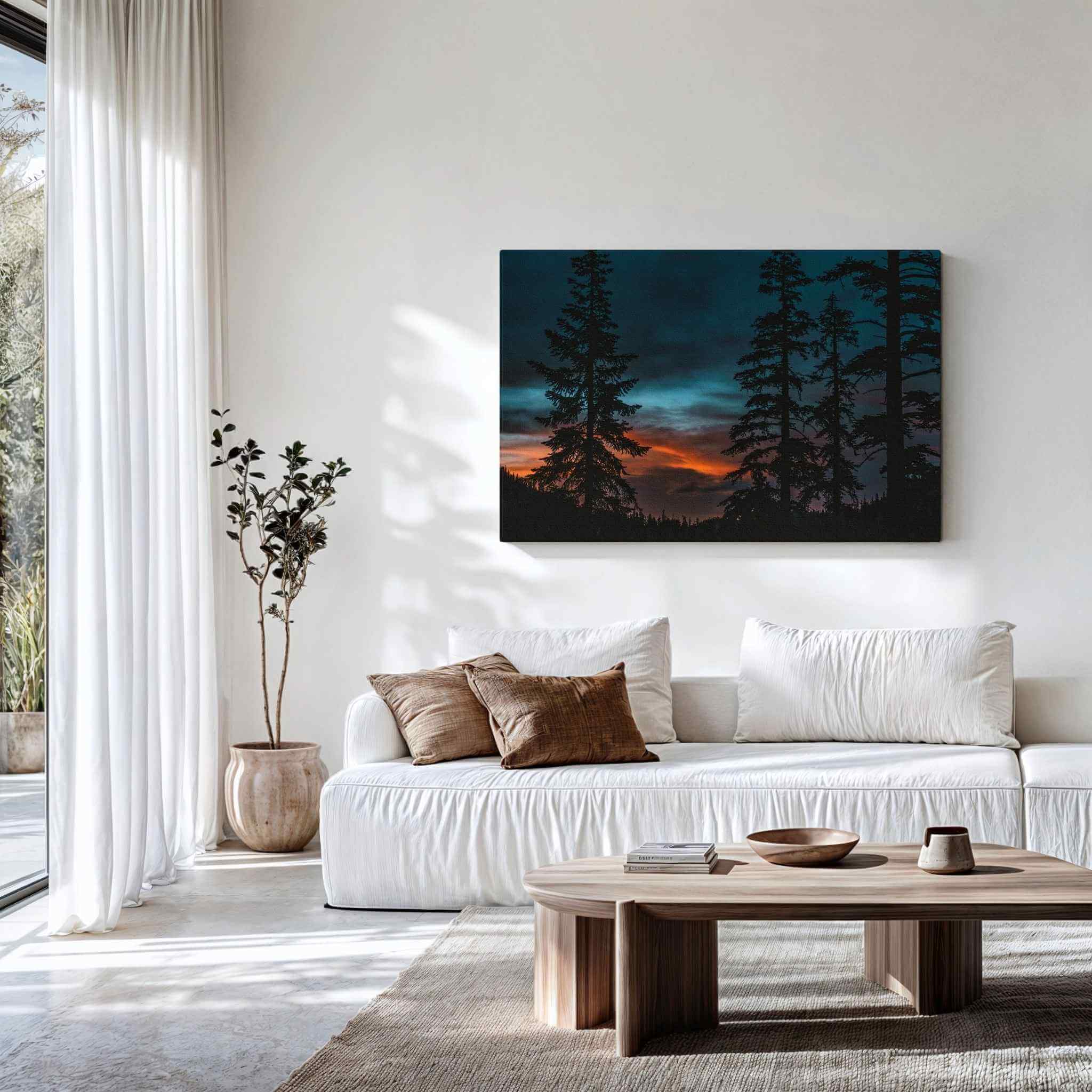 Gallery wrapped canvas of Blue Hour Among the Pines displayed above a contemporary white sofa, featuring silhouetted pine trees beneath a dramatic blue hour sky in Mammoth Lakes, California. Fine art wall decor by Abigail Diane Photography.
