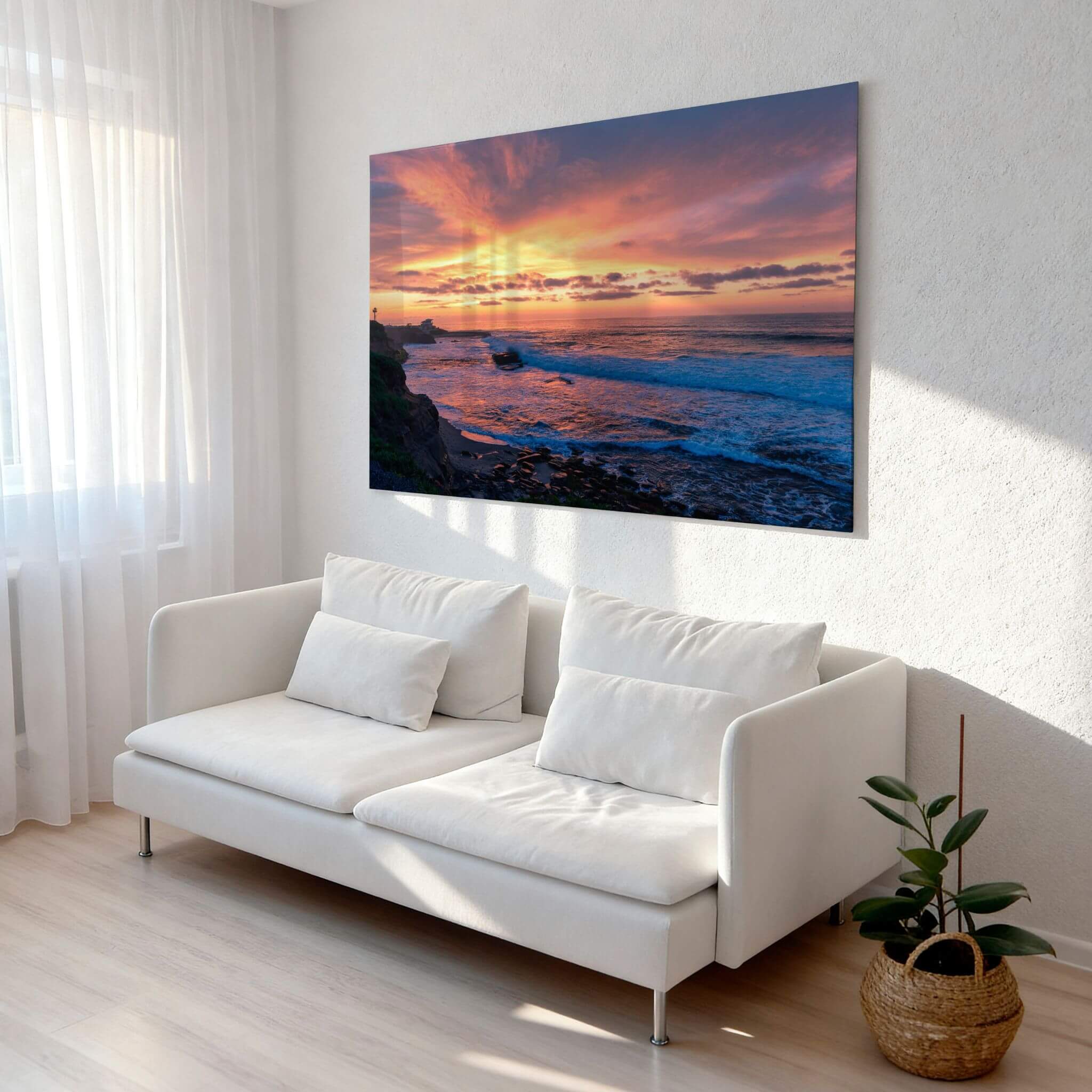 Candy Floss Sunset metal wall art displayed above a white sofa in a bright modern living room, featuring a colorful Laguna Beach sunset.