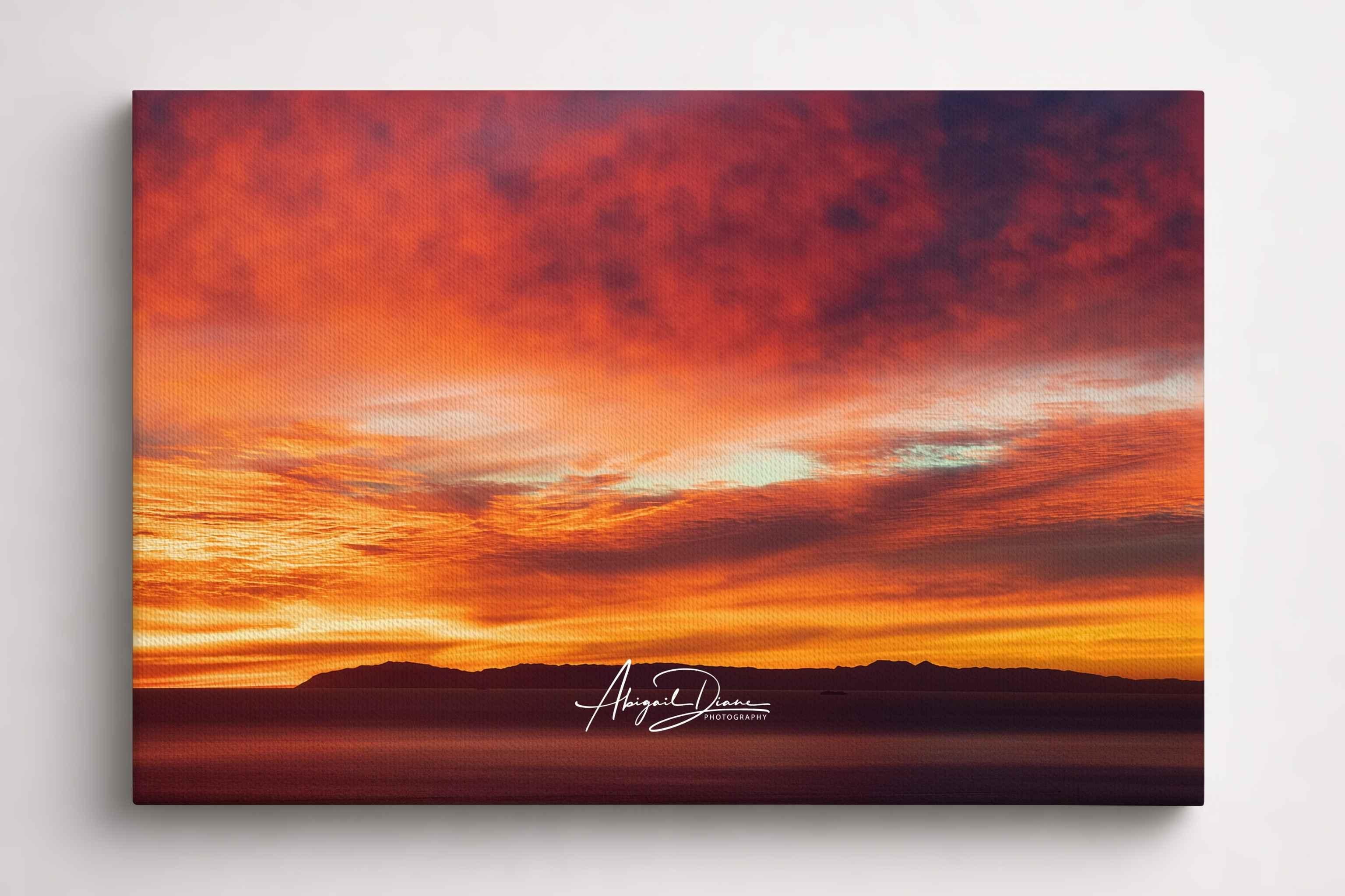 Catalina Beneath Crimson Skies captures vibrant crimson, orange, and golden clouds above Catalina Island in the Pacific Ocean at sunset. Gallery-wrapped canvas wall art by Abigail Diane Photography.