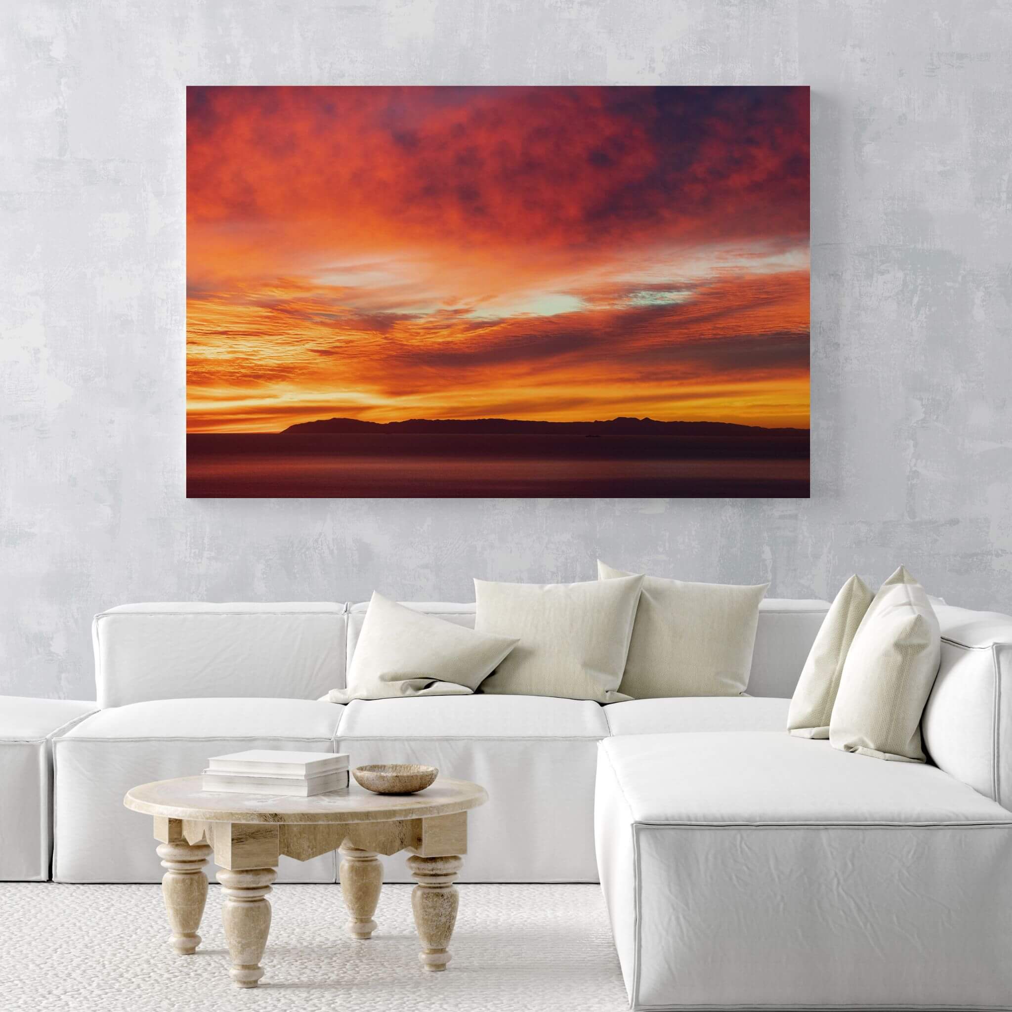 Large Catalina Beneath Crimson Skies metal wall art displayed above a white sectional sofa in a bright contemporary living room.