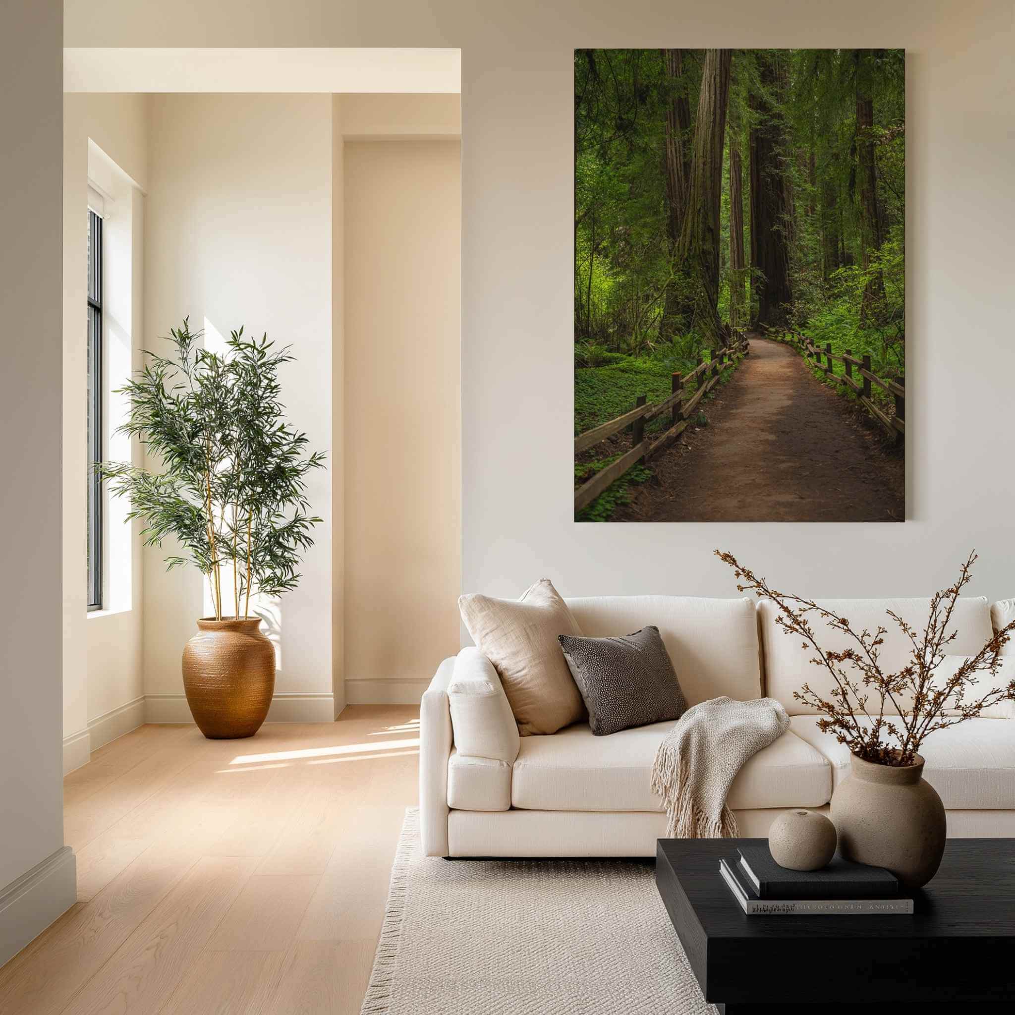 Cathedral of Giants metal print by Abigail Diane Photography displayed above a neutral sofa in a modern living room, featuring a peaceful redwood forest path in Muir Woods, California.