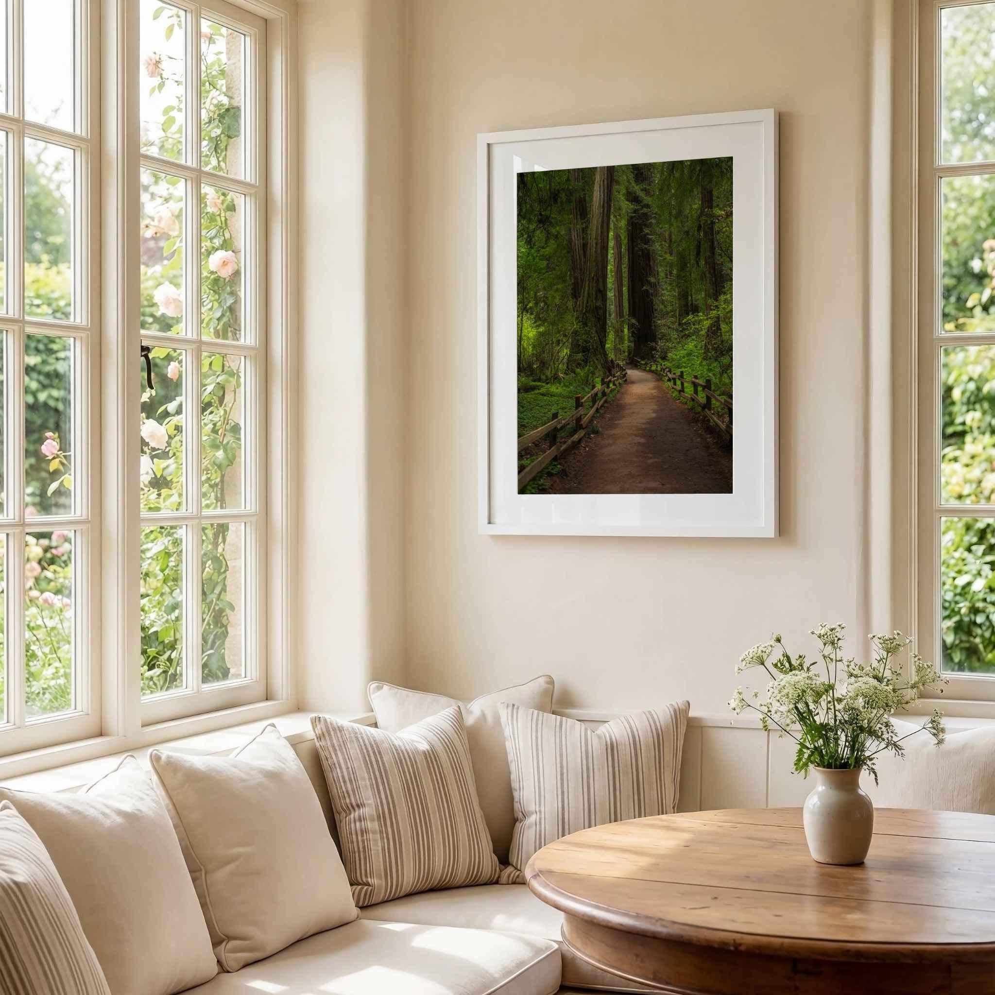 Cathedral of Giants by Abigail Diane Photography displayed in a white frame above a cozy dining nook with neutral cushions, natural wood furnishings, and soft floral accents, showcasing towering redwoods in Muir Woods California.