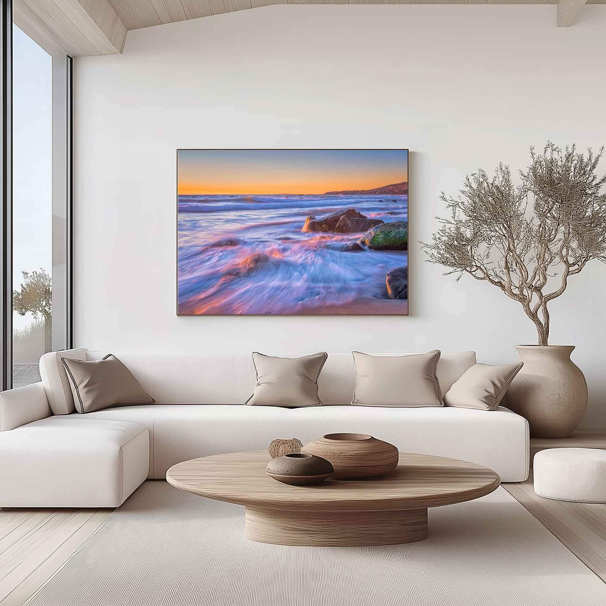 Large gallery-wrapped canvas print of Cotton Candy Waves by Abigail Diane Photography displayed above a cream sectional sofa in a contemporary living room, featuring a long-exposure seascape at Crescent Beach, Laguna Beach, California.