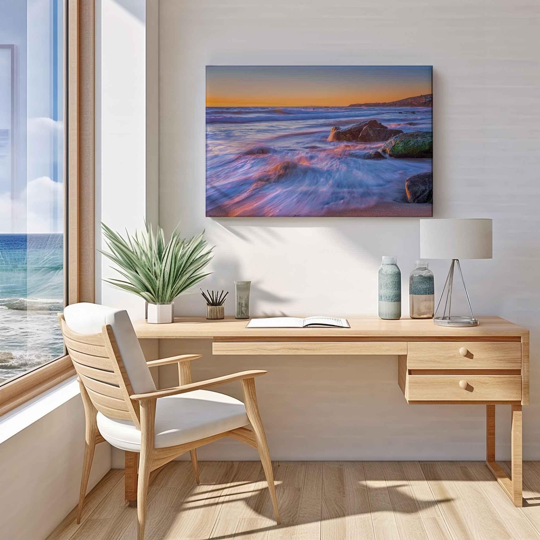 Large gallery-wrapped canvas print of Cotton Candy Waves by Abigail Diane Photography displayed above a wooden desk in a coastal home office, featuring a long-exposure seascape at Crescent Beach, Laguna Beach, California.