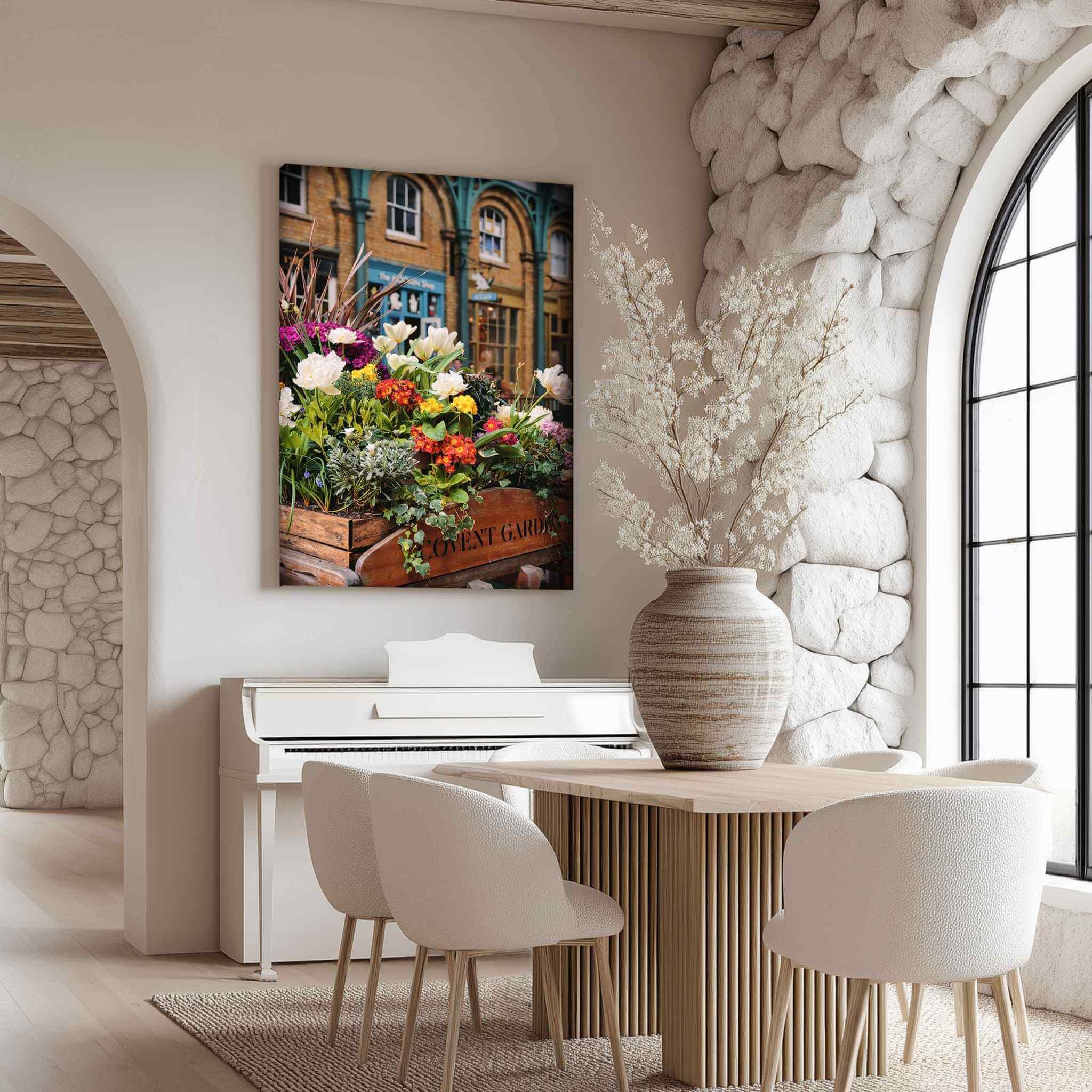 Covent Garden in Bloom by Abigail Diane Photography displayed as a vertical canvas wall art print in a bright modern dining room above a white piano, showcasing colourful spring flowers and historic Covent Garden architecture in London, England.