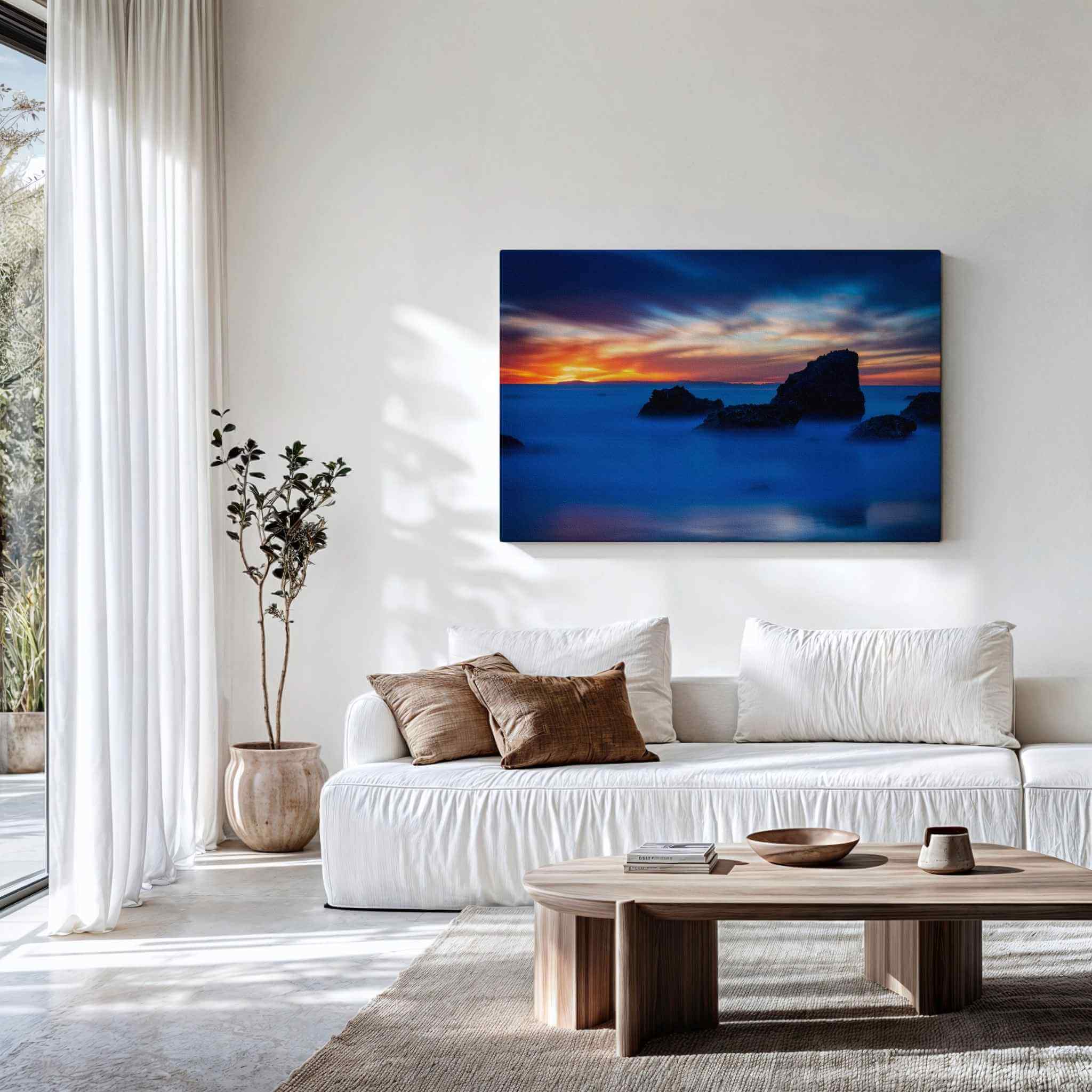 Gallery wrapped canvas of Escape to a Mystical Blue Hour displayed above a contemporary sofa, featuring a tranquil blue hour seascape with dramatic rocks along the Laguna Beach coastline, California. Fine art wall decor by Abigail Diane Photography.