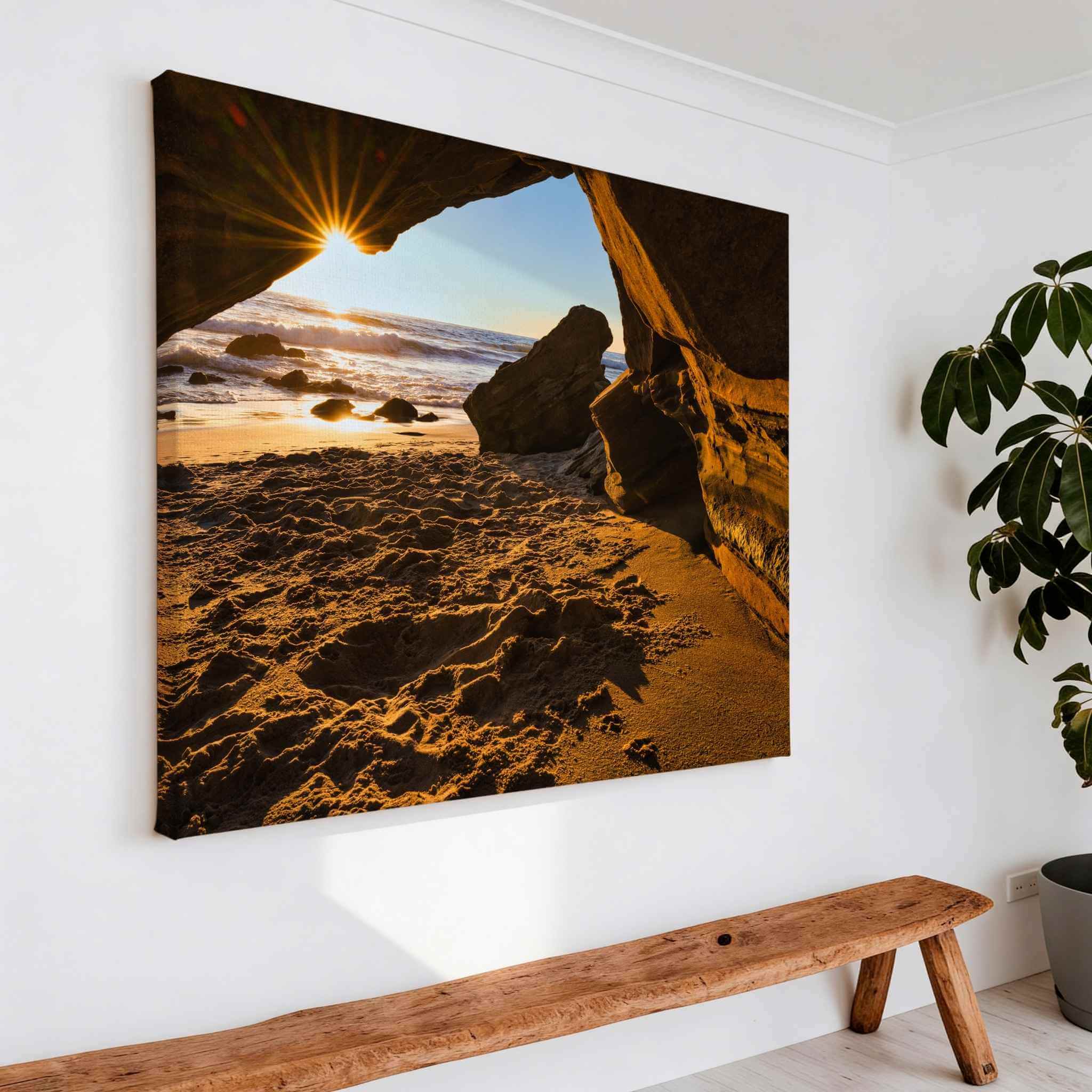 Gallery wrapped canvas of Golden Hour Sunburst displayed on a modern white wall, capturing sunlight shining through coastal sea caves at Laguna Beach, California. Fine art wall decor by Abigail Diane Photography.