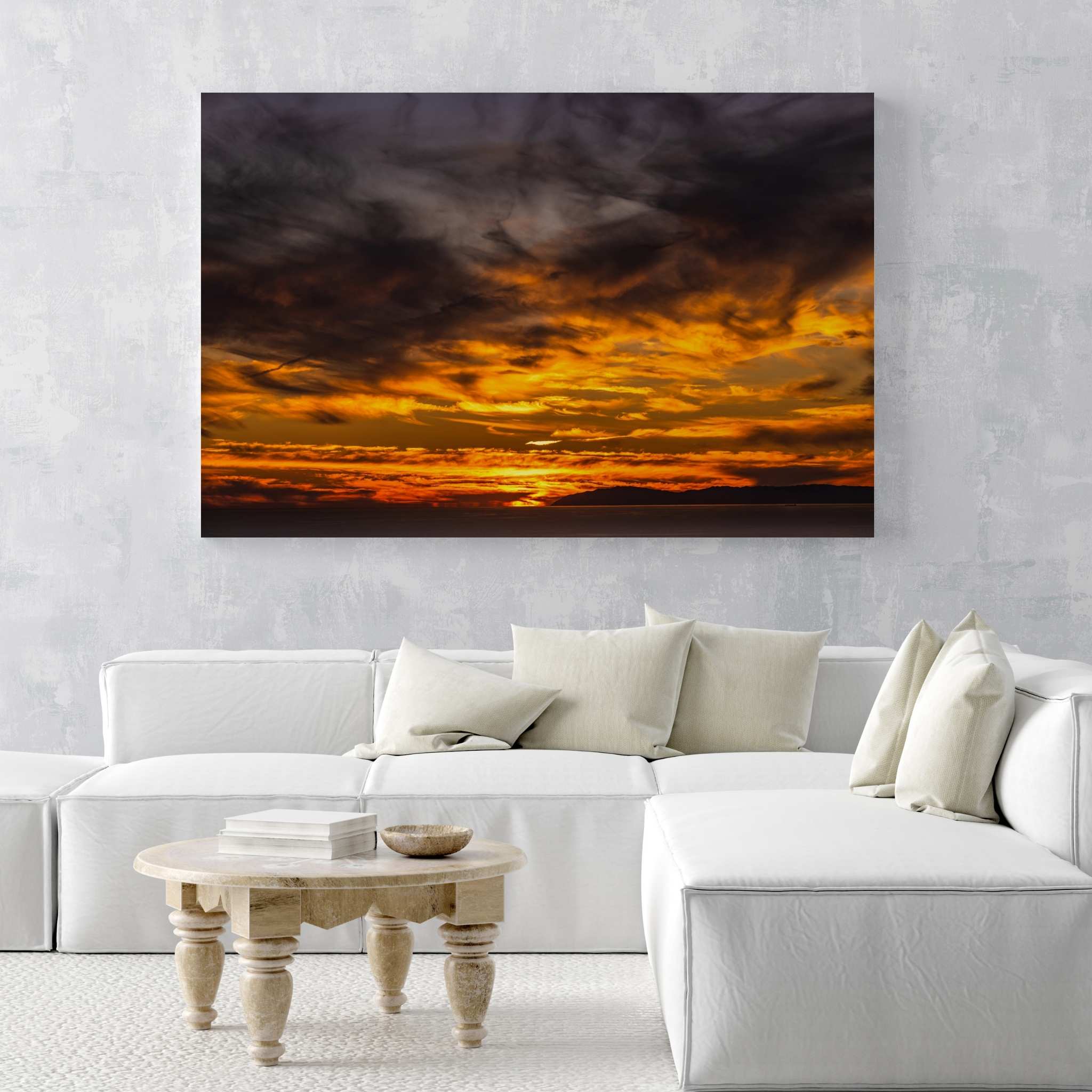 Gallery wrapped canvas featuring a dramatic golden sunset displayed above a white sectional sofa in a contemporary living room with a light stone coffee table.