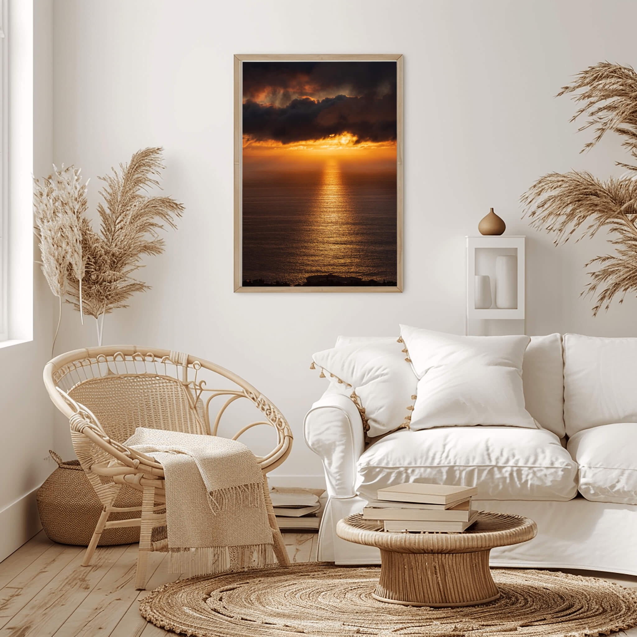 Golden Rays on the Mirrored Sea of the Pacific by Abigail Diane Photography, warm ocean sunset wall art in a neutral boho living room above a soft white sofa with cushions, rattan chair, woven coffee table, pampas grass decor and natural textures creating a calm coastal atmosphere.