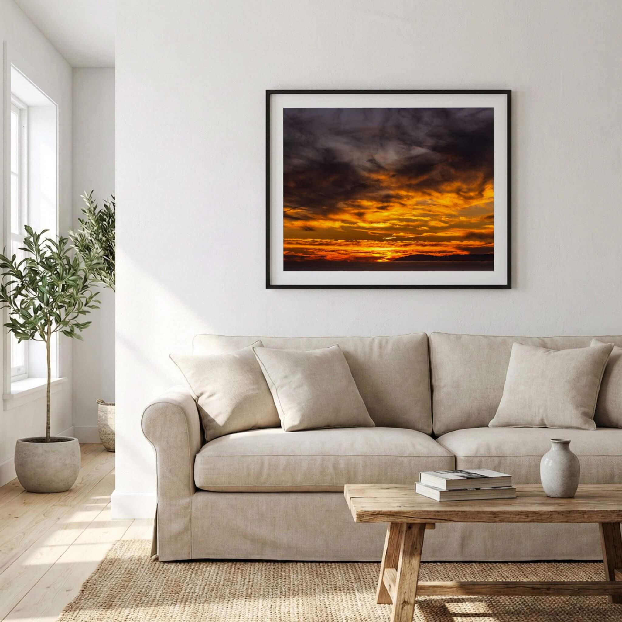 Golden sunset cloudscape wall art displayed in a bright living room, featuring dramatic golden clouds, a fiery sunset sky, and the Pacific Ocean beyond the California coastline.