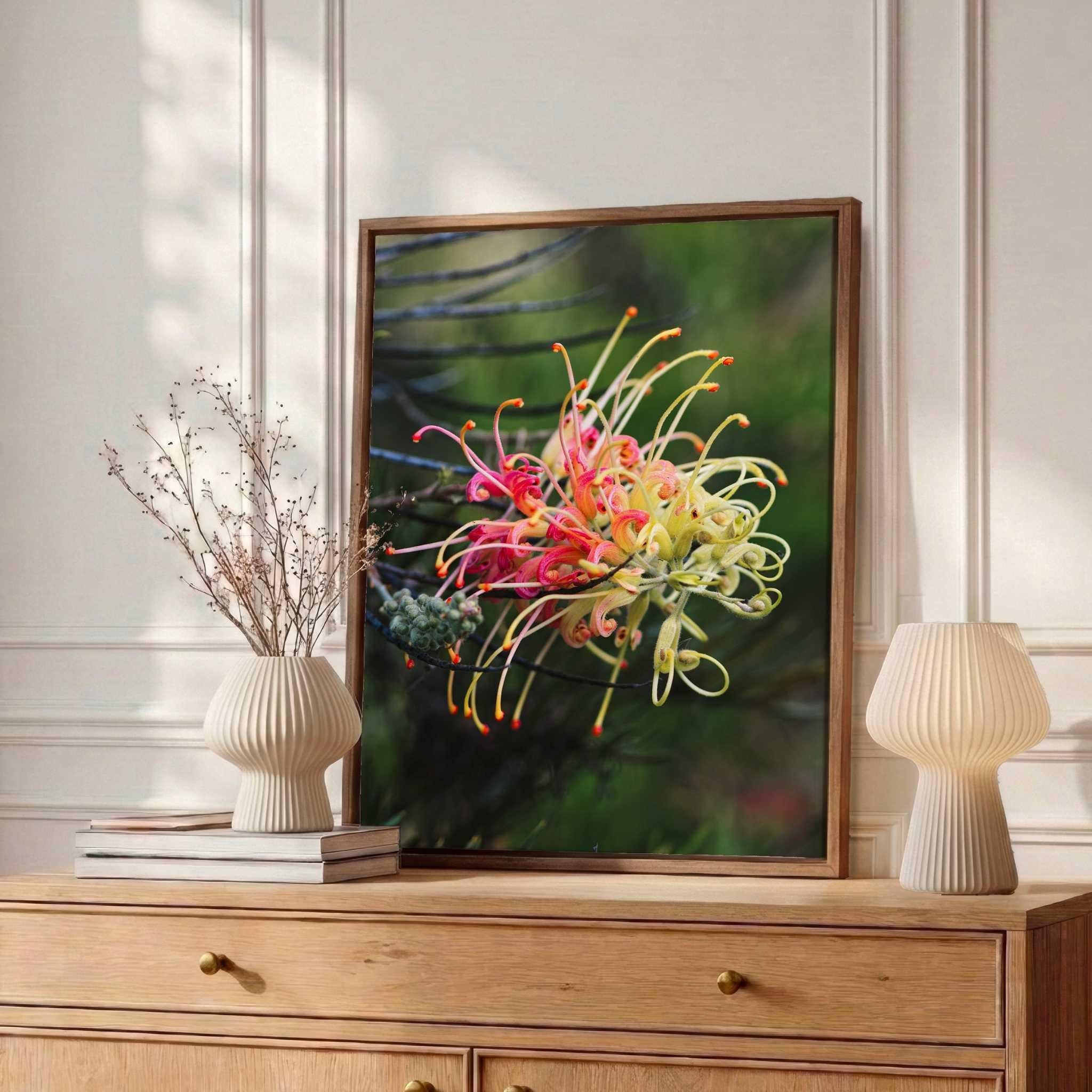 Framed fine art print of a Grevillea Peaches and Cream flower displayed on a light oak dresser with ceramic décor in a warm, sunlit bedroom, styled by Abigail Diane Photography.