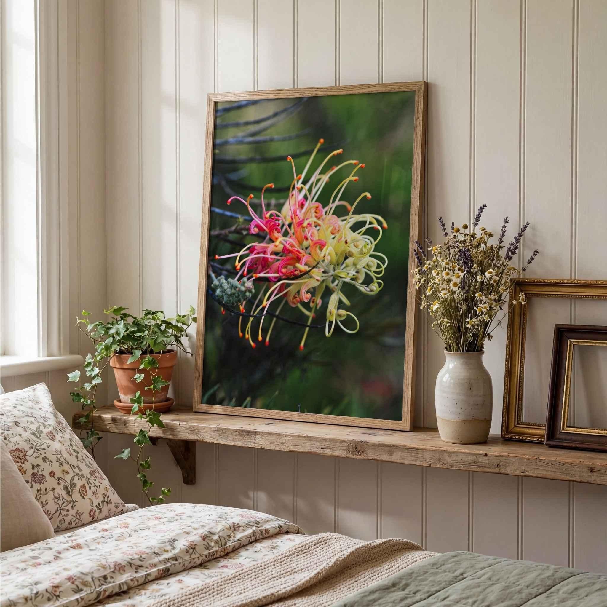 Grevillea Peaches and Cream fine art print in a natural oak frame leaning on a rustic wooden shelf in a cozy bedroom with dried flowers, botanical accents, and soft neutral textiles by Abigail Diane Photography.