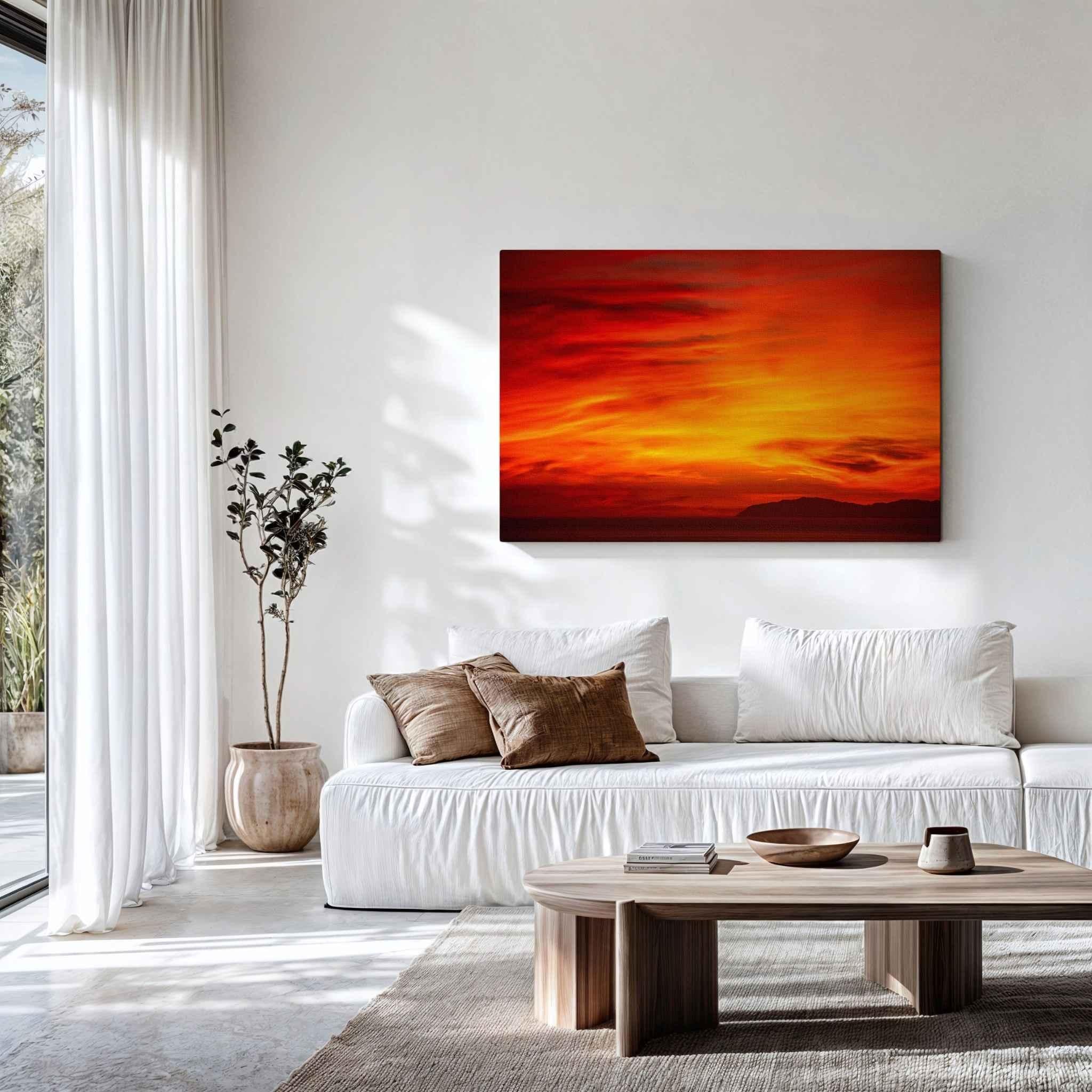 Gallery-wrapped canvas of Inferno Sunset displayed above a white sofa in a light-filled contemporary living room, featuring dramatic crimson and golden sunset skies over Catalina Island along the California coast. Fine art canvas wall décor by Abigail Diane Photography.
