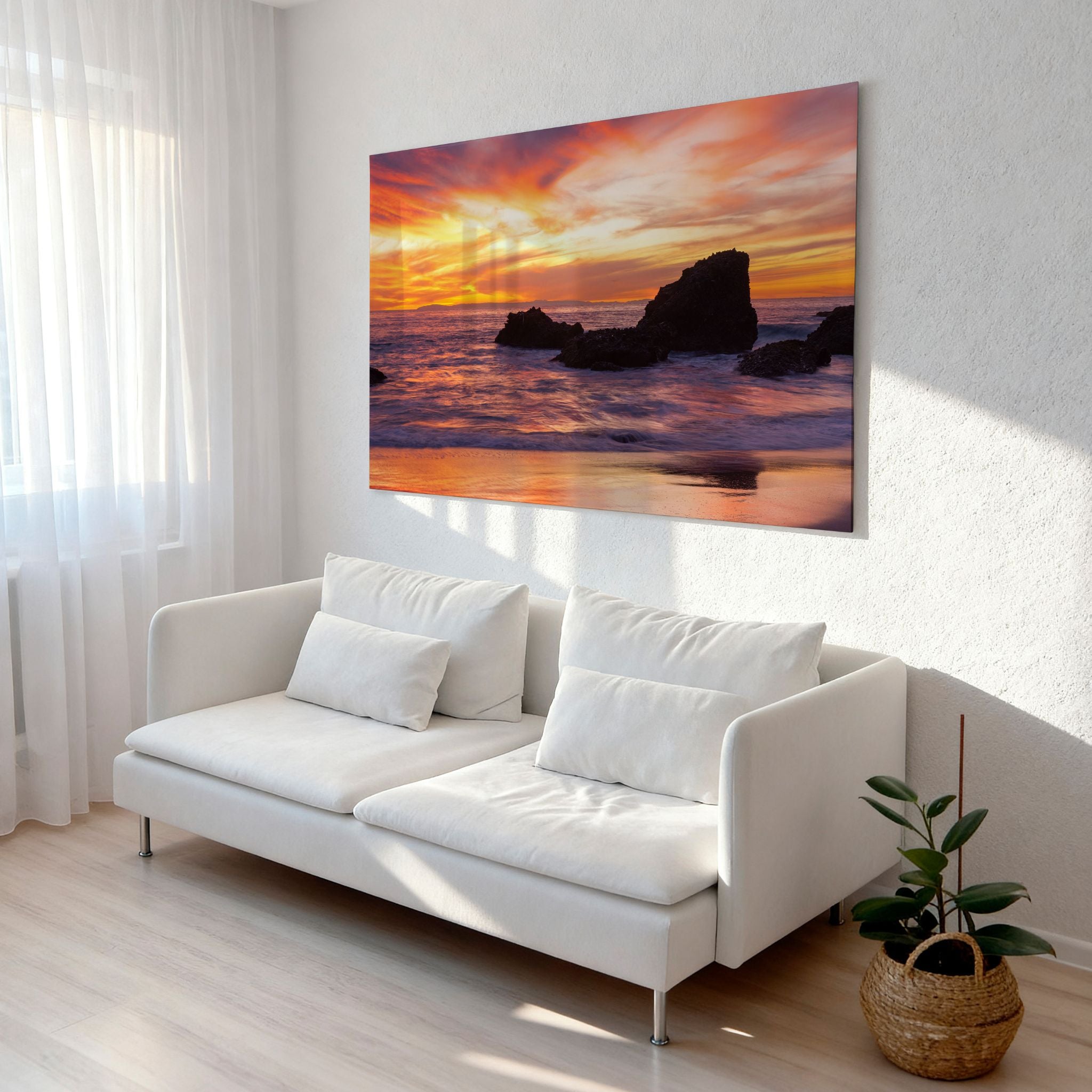 Modern living room featuring HD metal wall art of Woods Cove Beach, Laguna Beach, California, with a vibrant sunset, glowing ocean reflections, and dramatic coastal rocks by Abigail Diane Photography.
