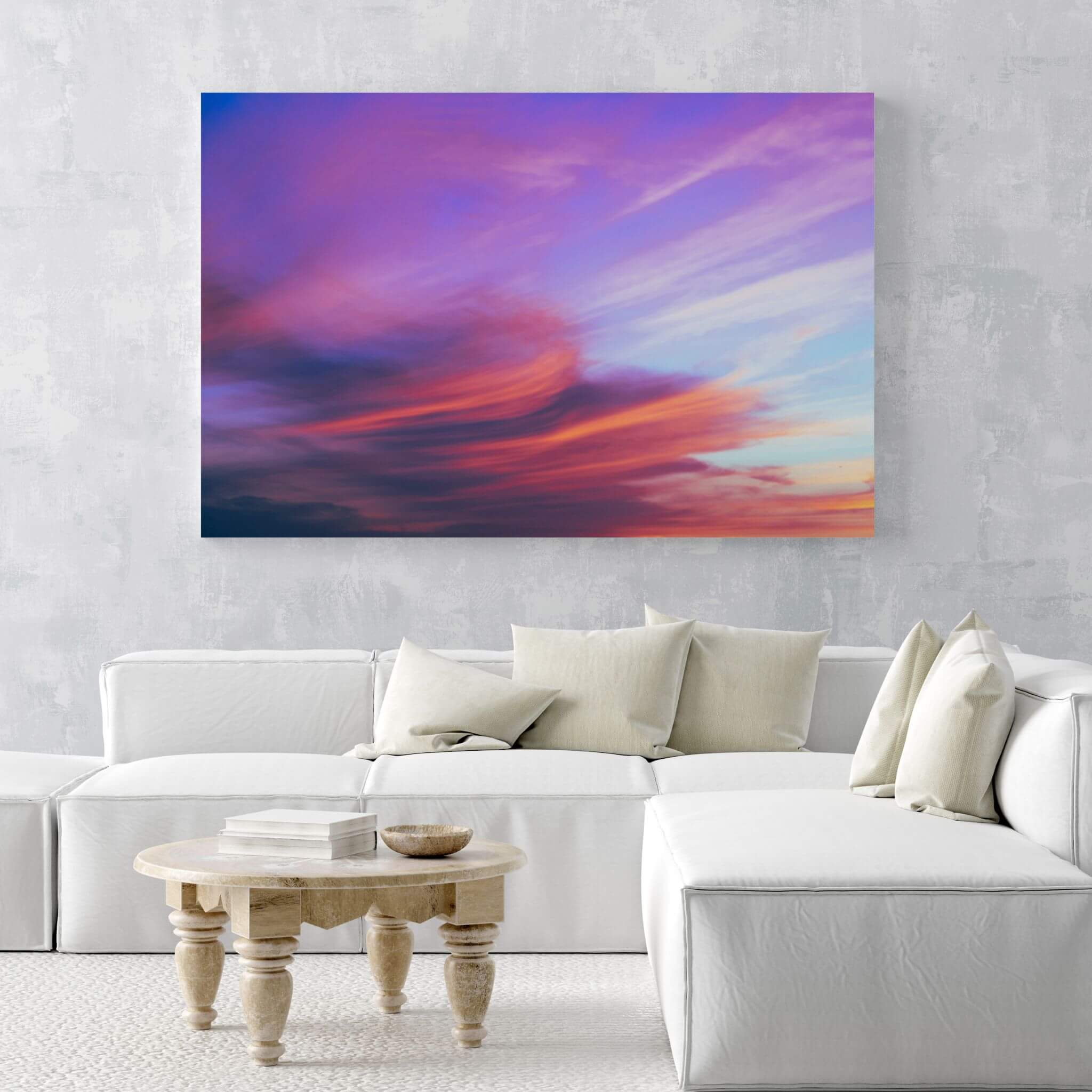 Lavender Dreams HD metal wall art displayed above a contemporary white sofa, featuring flowing lavender, pink, coral, and blue sunset clouds. Nature-inspired photography by Abigail Diane Photography