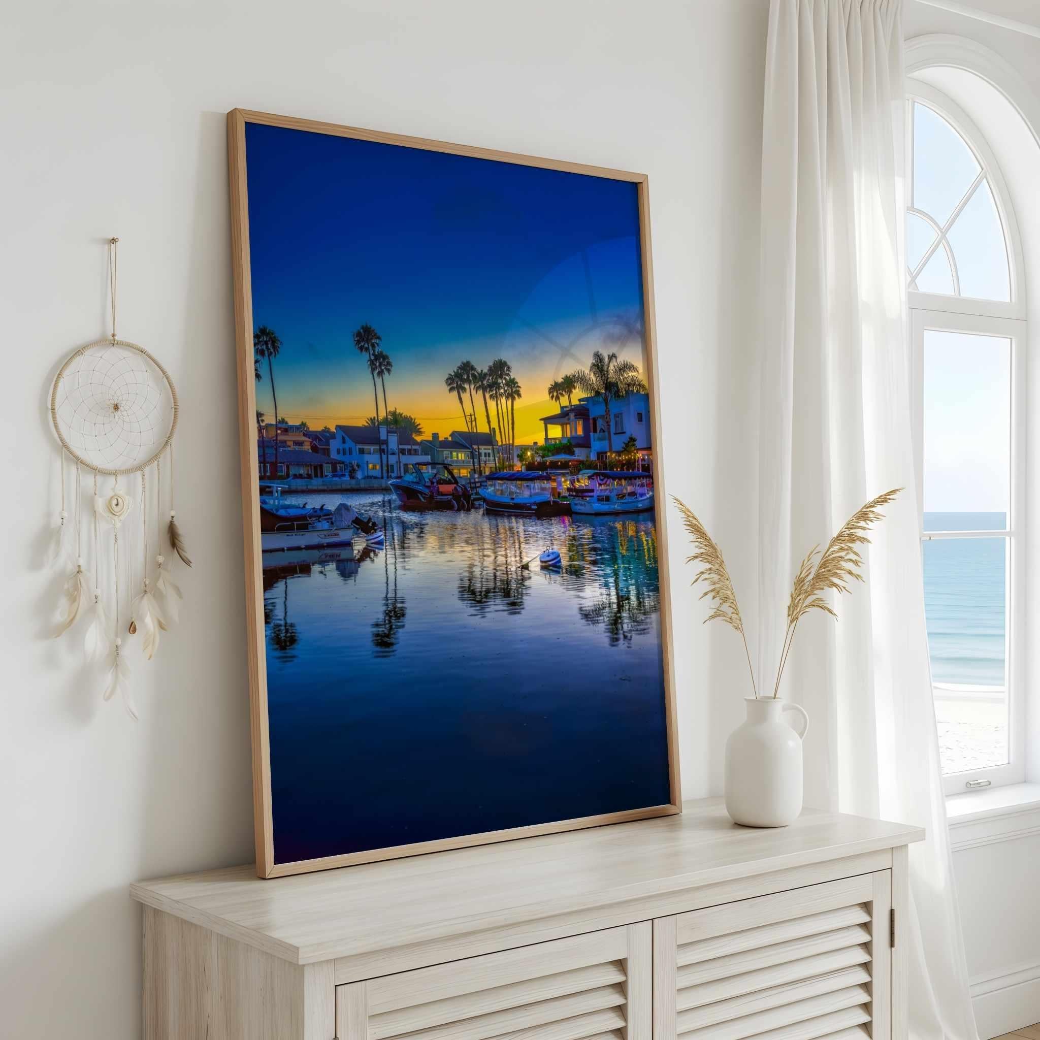 Magic of the Blue Hour by Abigail Diane Photography displayed in a light oak frame above a coastal console, overlooking the beach through sunlit windows.
