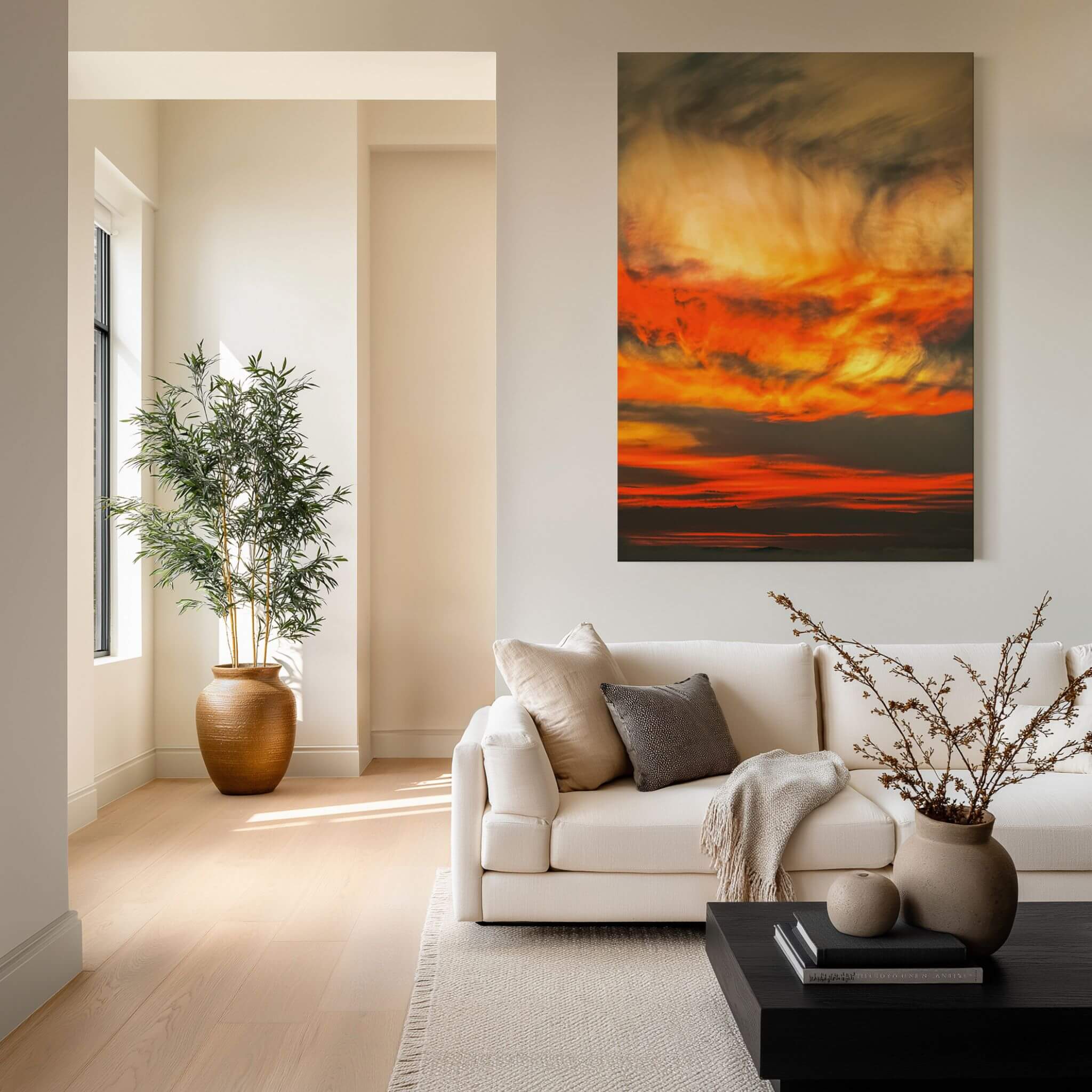 Painted Lady High Definition metal print by Abigail Diane Photography, featuring dramatic golden yellow, fiery orange and deep charcoal sunset clouds, displayed above a cream sofa in an elegant neutral living room with natural wood, soft textiles and greenery.