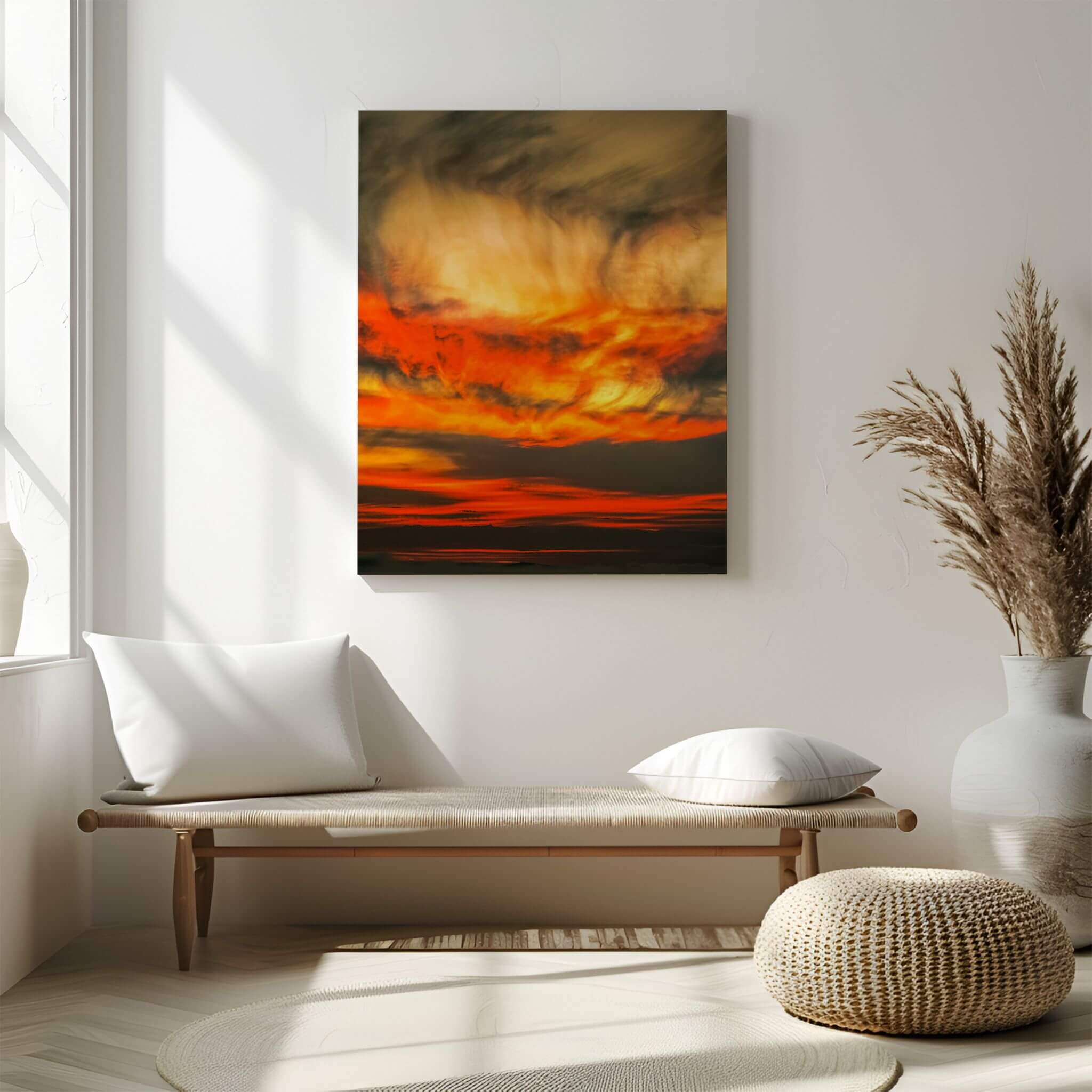 Painted Lady High Definition metal print by Abigail Diane Photography, featuring dramatic golden yellow, fiery orange and deep charcoal sunset clouds, displayed above a natural wood bench in a serene neutral interior with soft sunlight, cream textiles and decorative pampas grass.