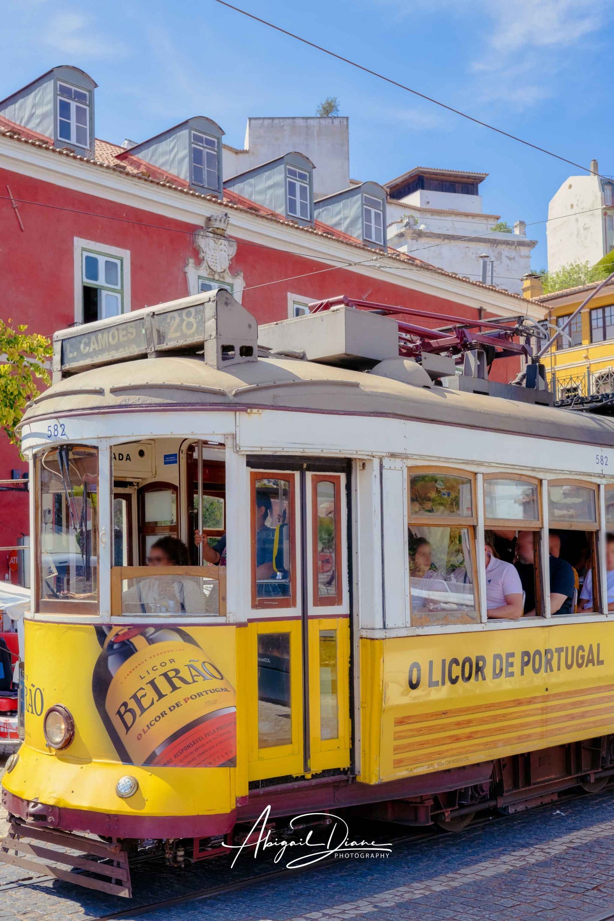 Riding Through Lisboa featuring a classic yellow tram passing colorful historic buildings in Lisbon, Portugal – Abigail Diane Photography