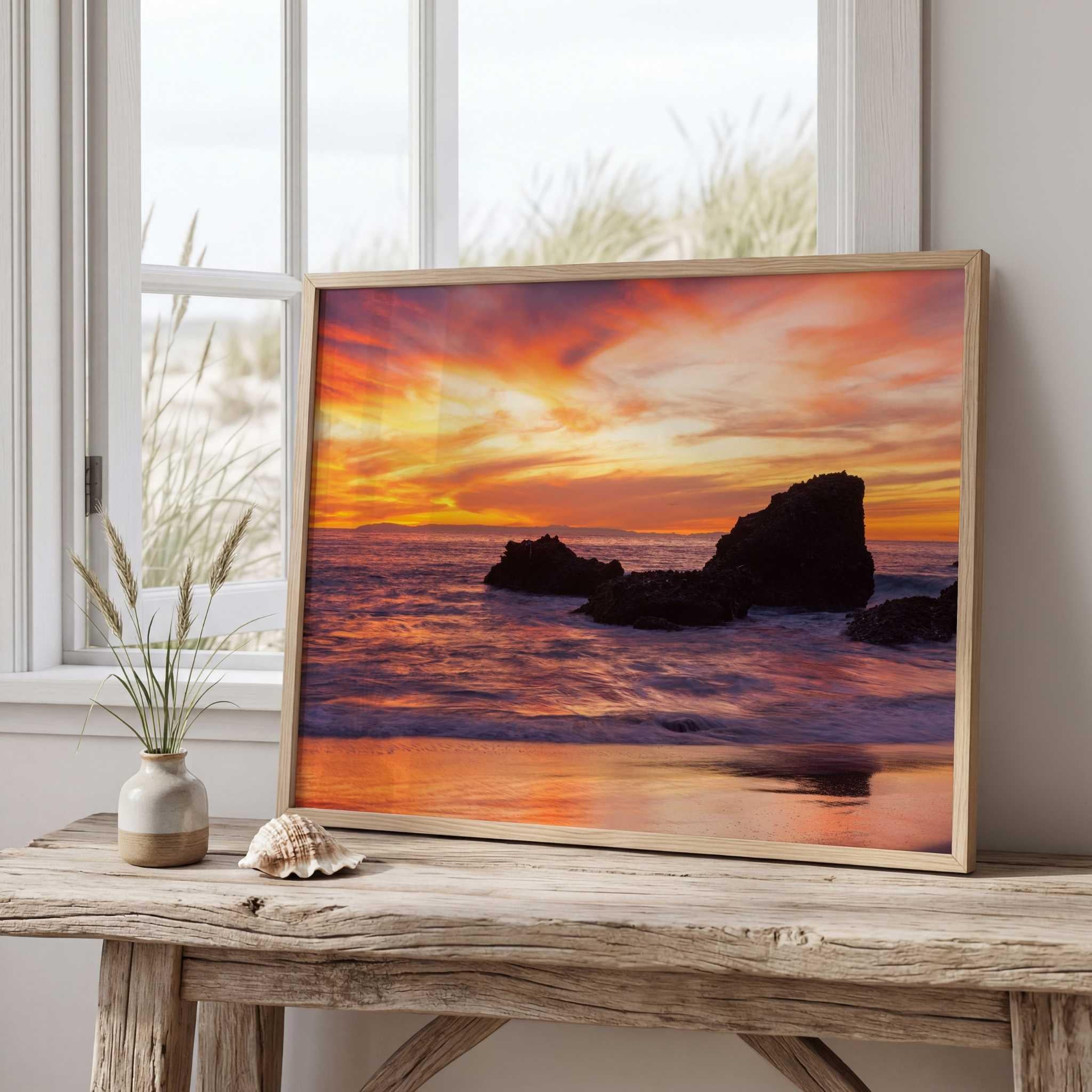 Sherbet Sunset fine art print featuring vibrant orange and pink sunset skies over the rocky coastline of Laguna Beach, California displayed as coastal wall art in a bright beach-inspired living room.
